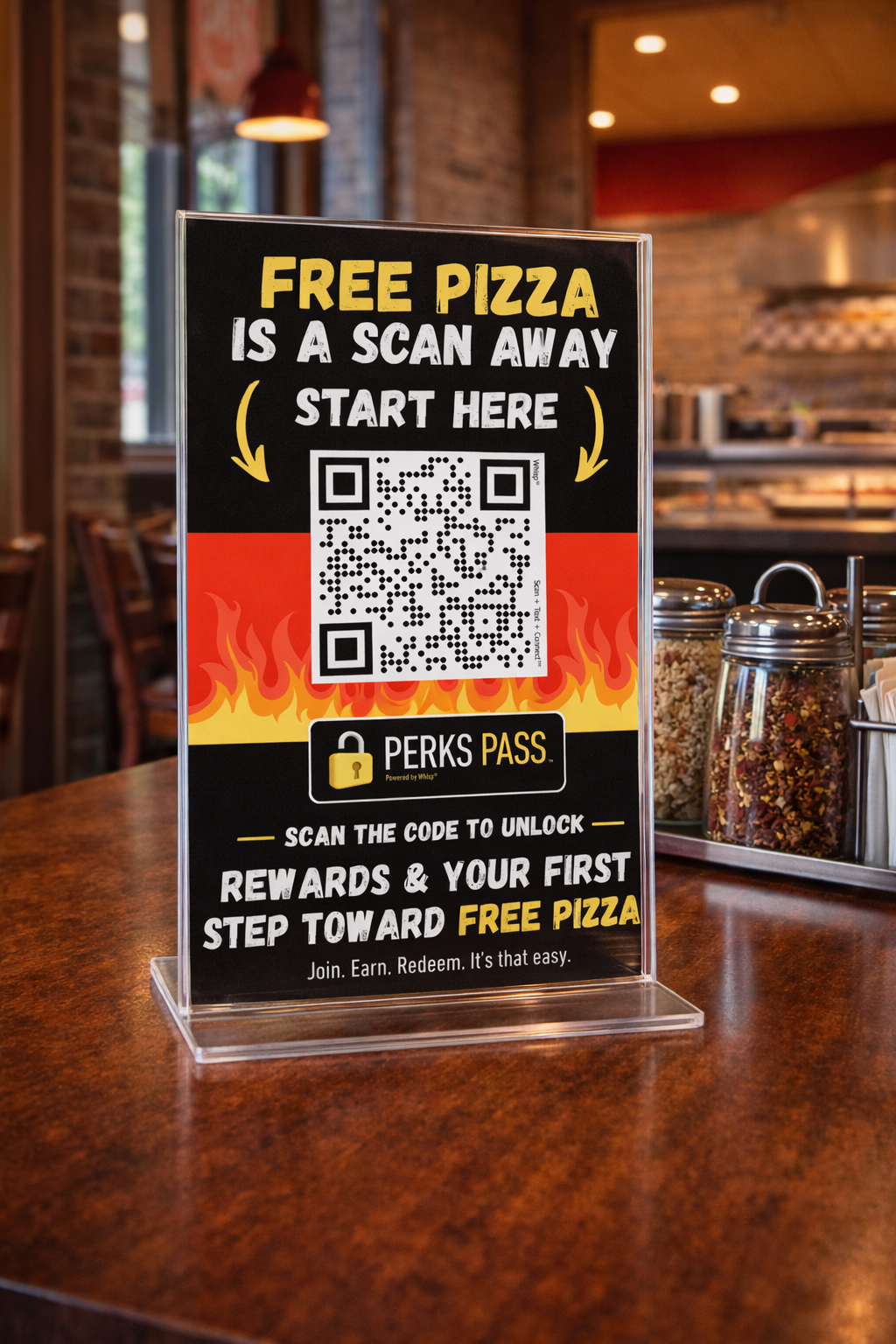 A promotional sign inside a restaurant advertising a QR code for a rewards program to earn a free pizza. The sign features a black background with flames at the bottom, yellow and white text, and a QR code in the center.