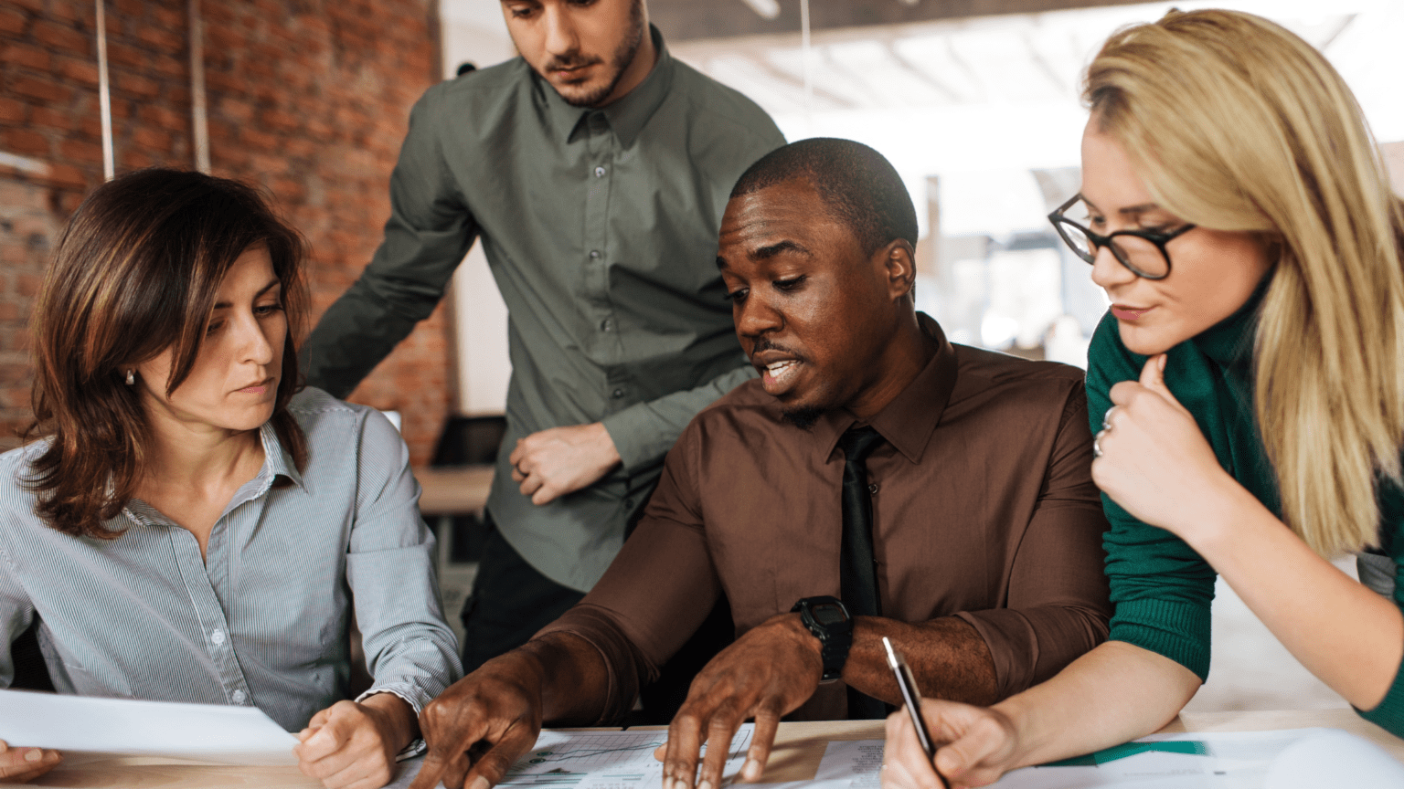 Man explaining a project to team members during a workplace meeting.