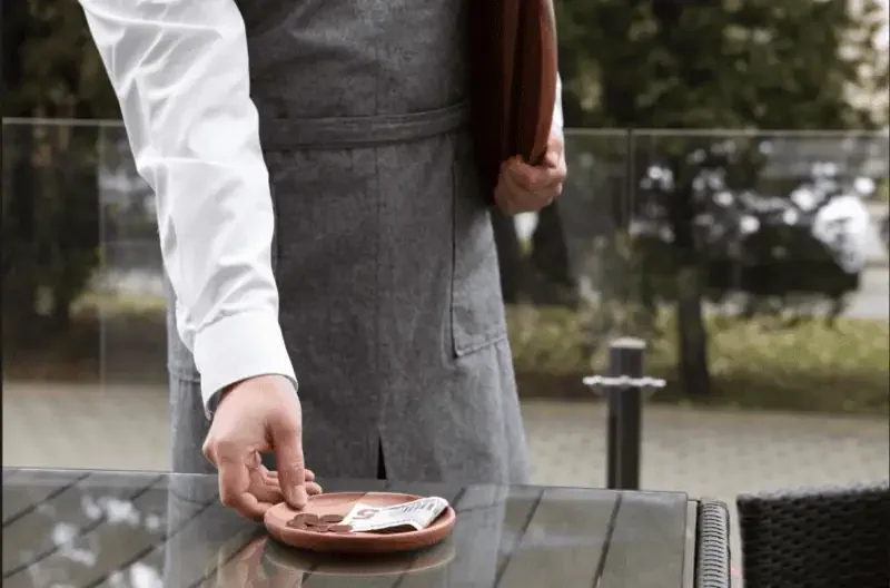 Waiter collecting a tip left on a restaurant table.