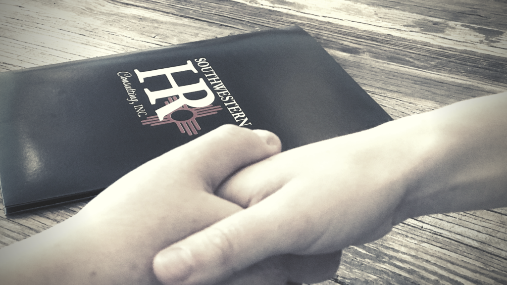 Two people shaking hands with a Southwestern HR booklet in the background
