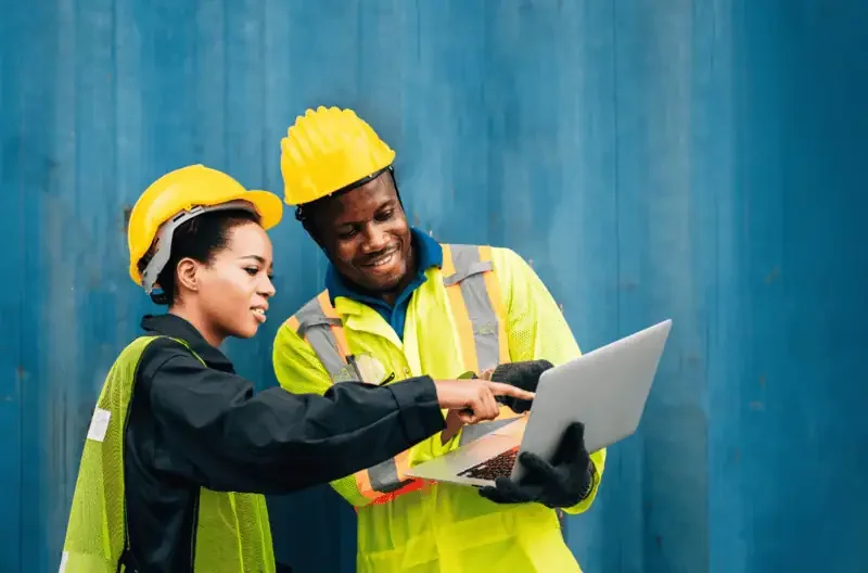 Two workers discussing work while viewing a laptop screen