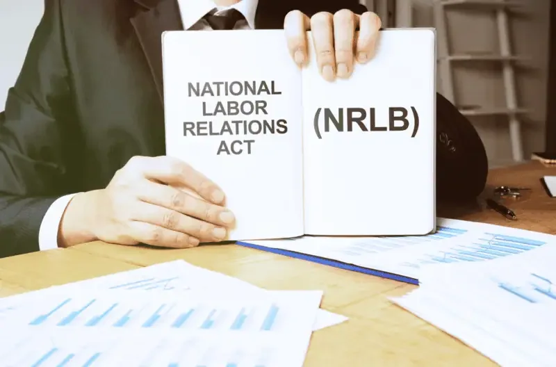 A man holding a notebook displaying the text 'National Labor Relations Act.'