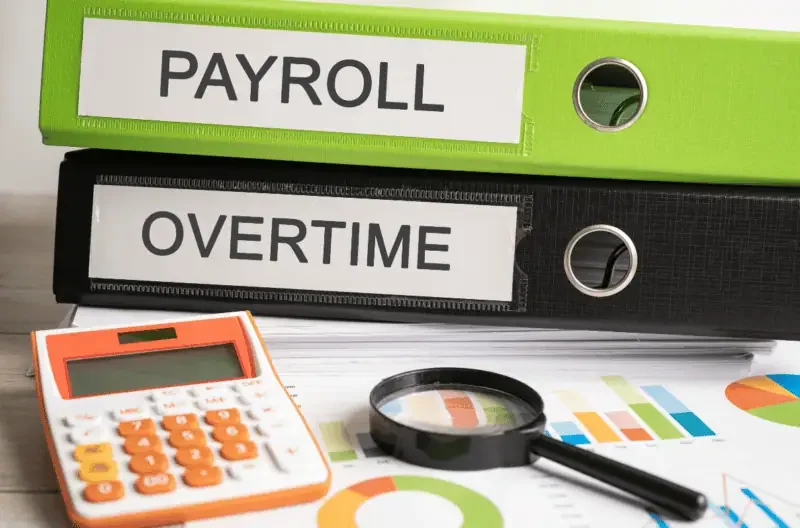 Payroll and overtime binder displayed on an office desk