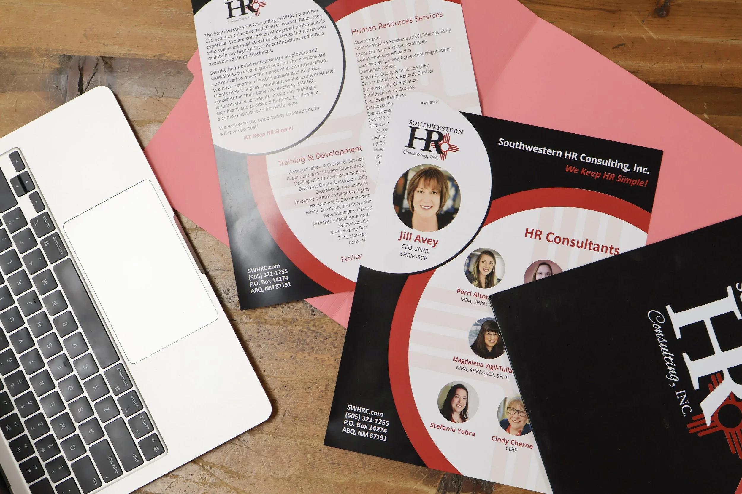 Brochures for Southwestern HR Consulting, Inc. with contact information, featuring images of women, and text about HR services and training programs, next to a silver laptop on a wooden table.