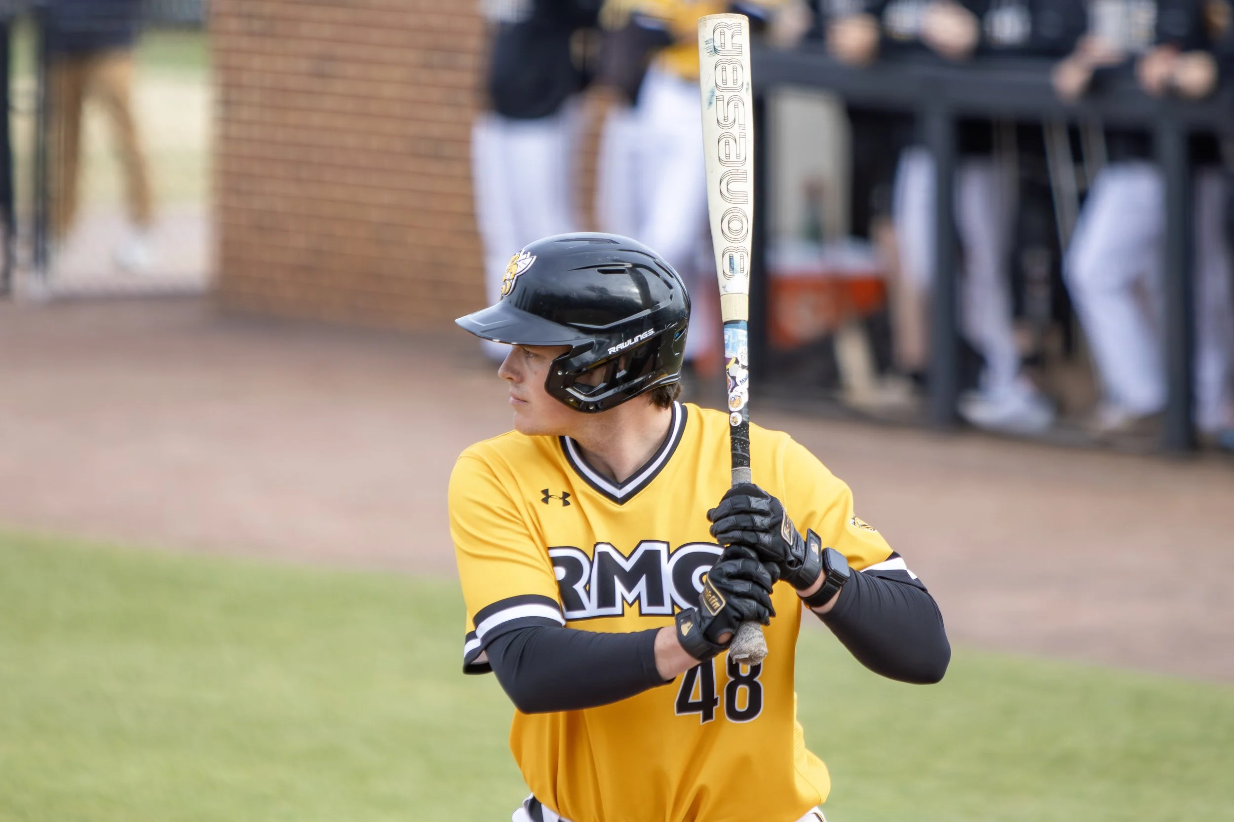 A baseball player in a yellow uniform with number 48 and arm sleeves, wearing a black helmet, standing at bat ready to hit during a game.