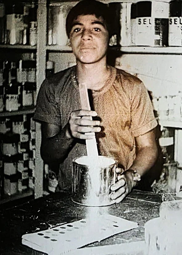 Joven Gaspar Téllez preparando y mezclando pintura durante sus primeros años de aprendizaje en el negocio familiar.