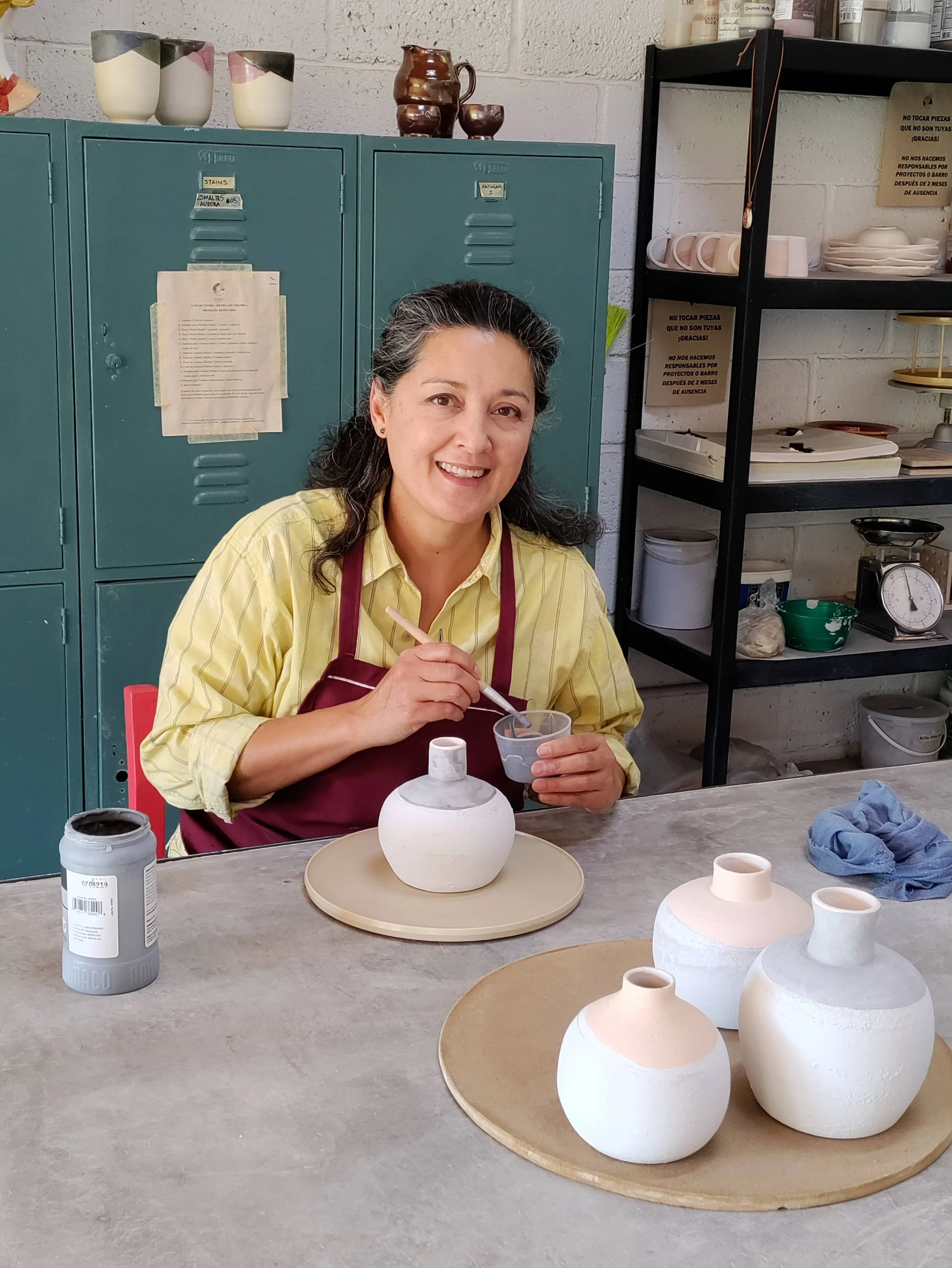 Fatimah Araneta applying glaze to a handmade ceramic piece in the Gaspart Studio ceramics workshop, where she teaches students traditional and contemporary pottery techniques.
