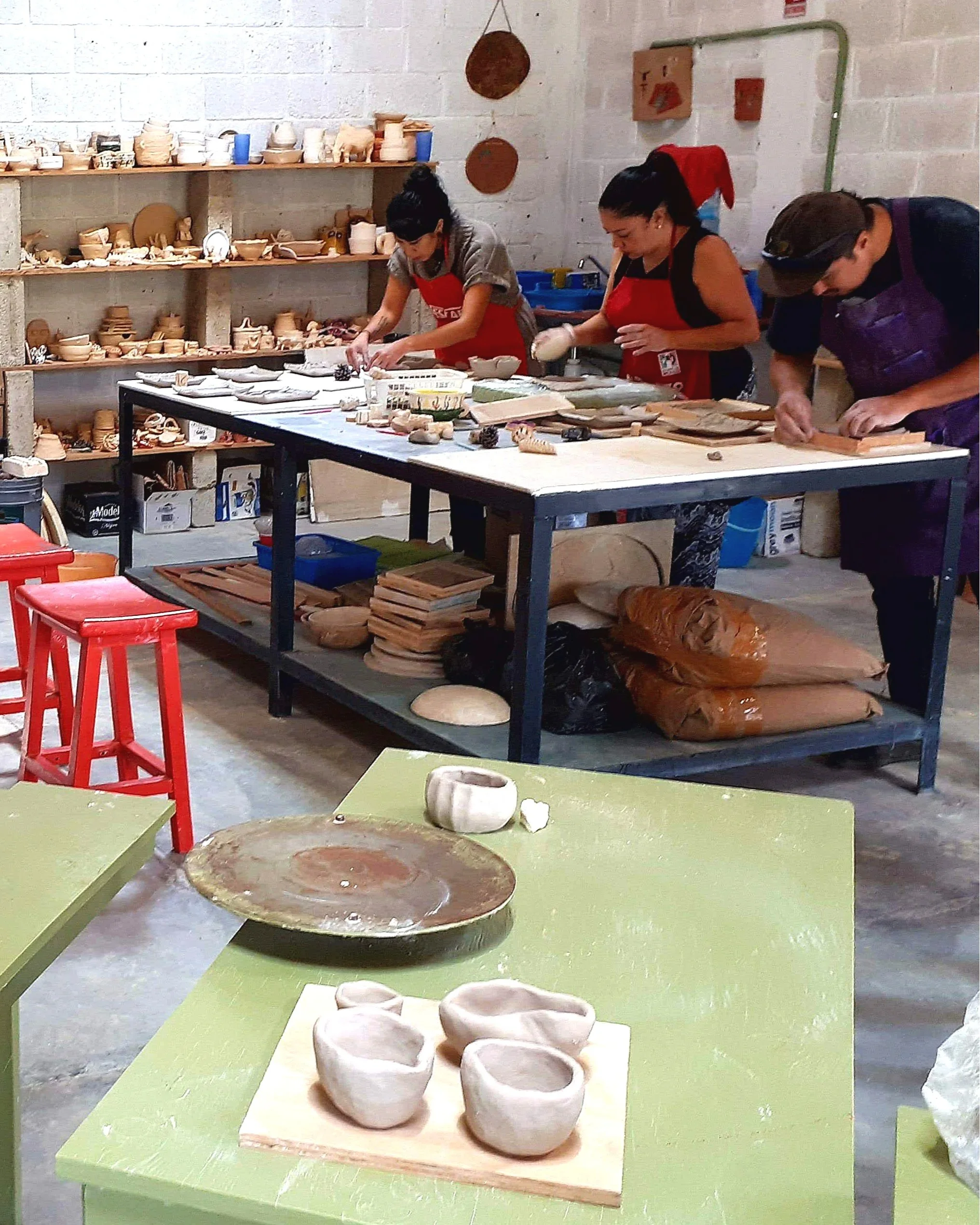 Niños y adultos trabajando en proyectos durante una clase de cerámica en Valle de Bravo.
