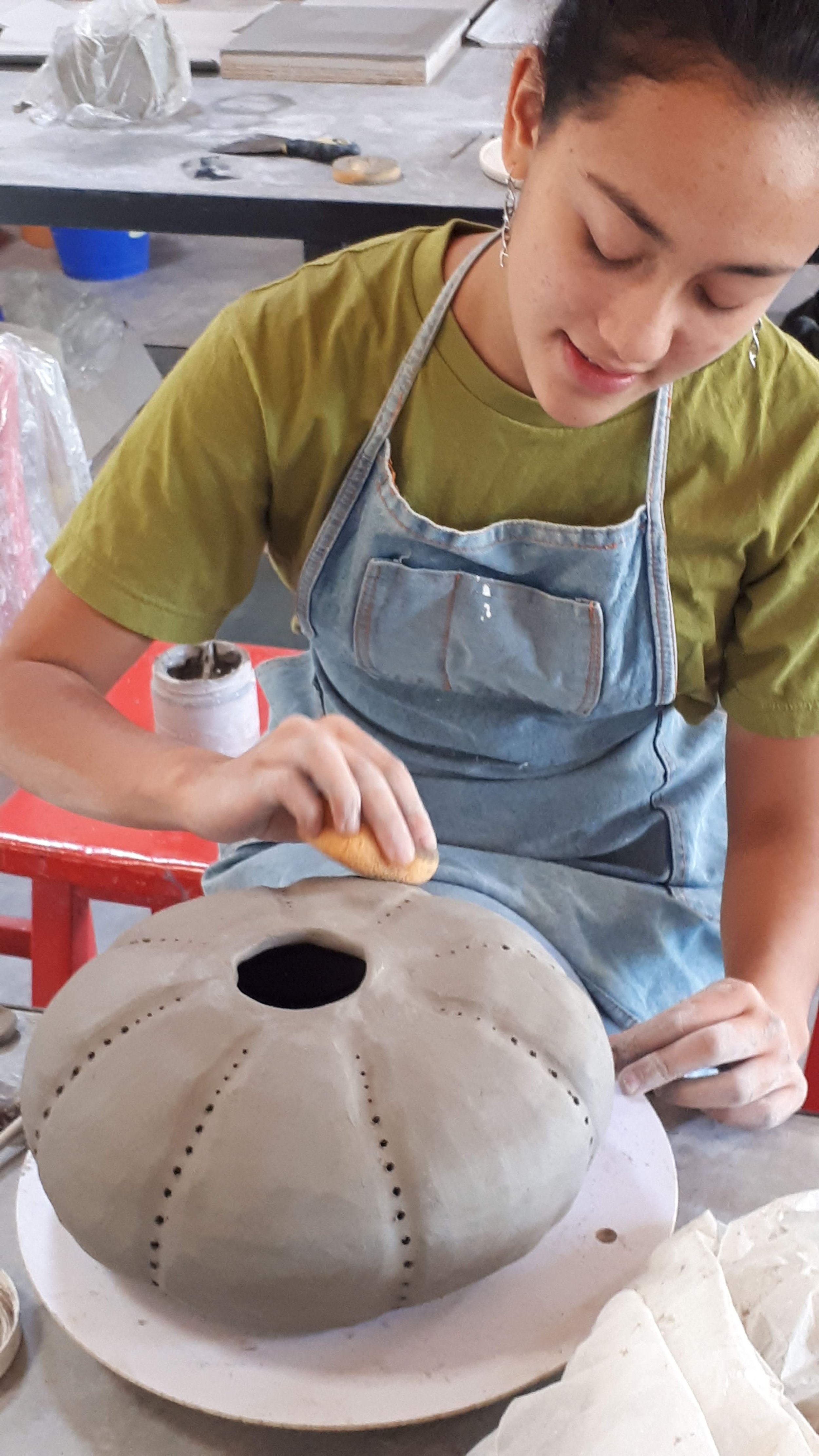 Aurora trabajando a mano una pieza de cerámica durante un taller.