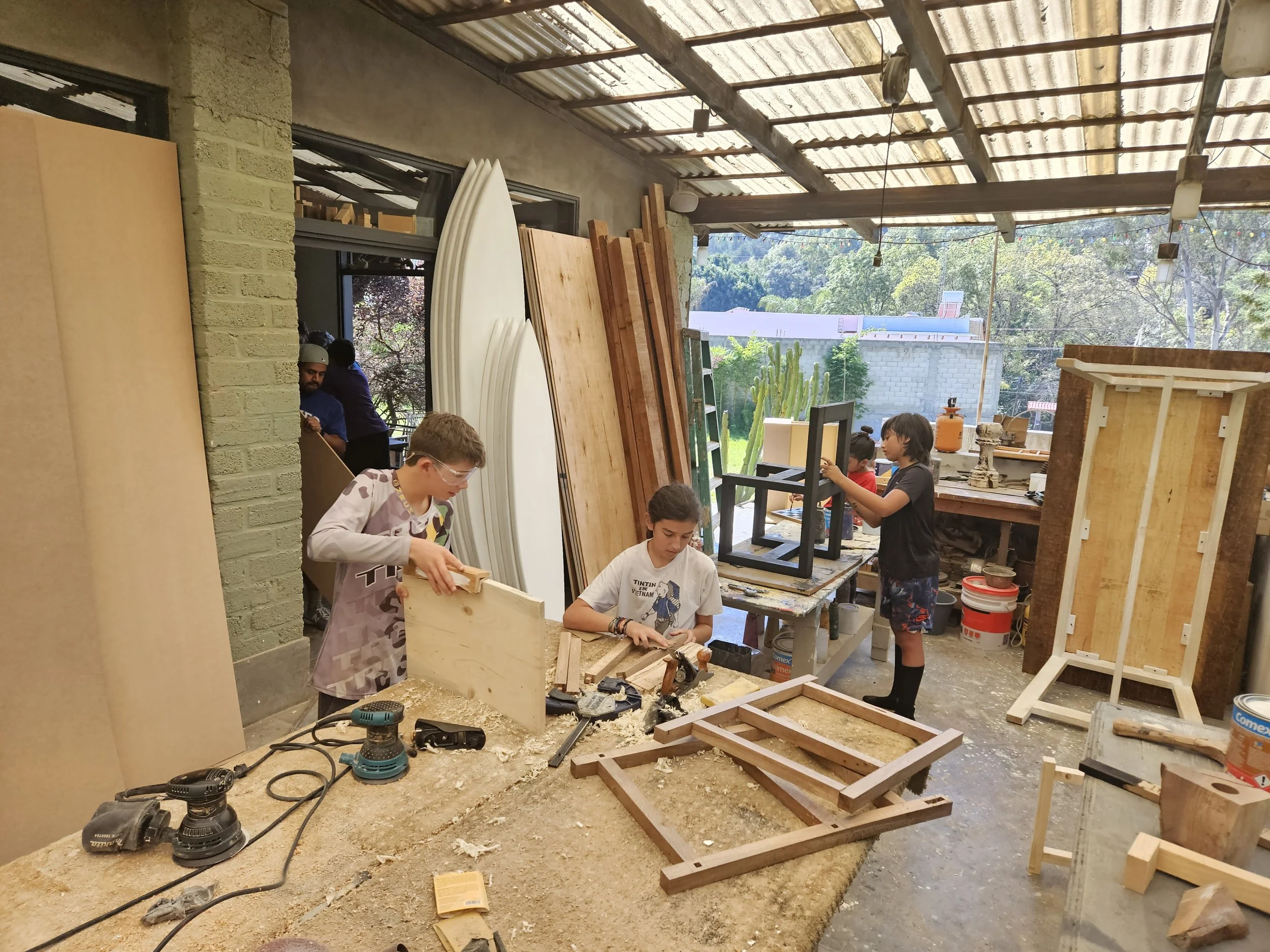 Niños trabajando en proyectos de madera con herramientas durante un campamento de verano en el taller de Gaspart Studio.