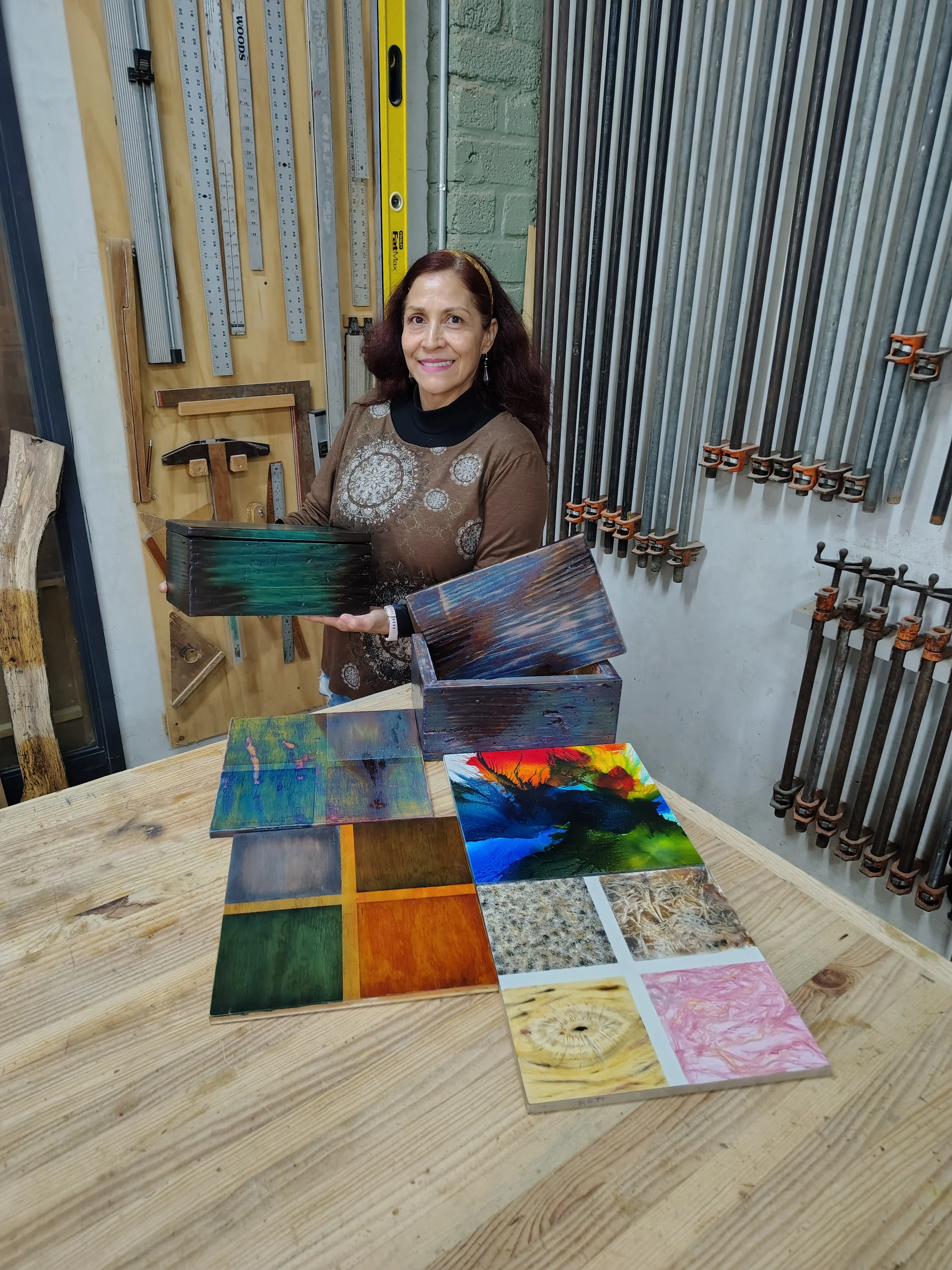Estudiante mostrando muestras de diferentes acabados y colores aplicados sobre madera durante un curso de acabados para madera en Gaspart Studio.