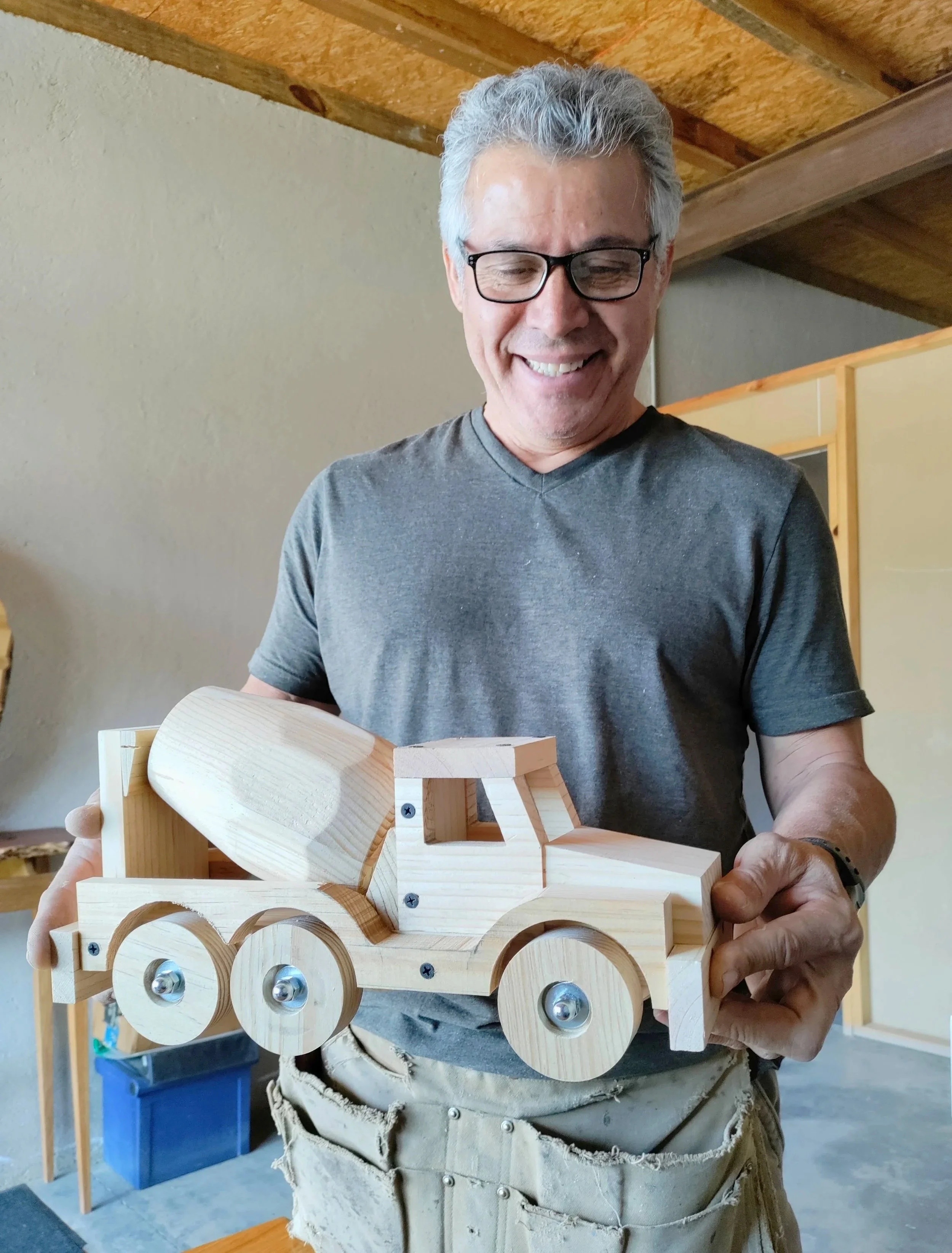 Gaspar Téllez sonriendo mientras sostiene un camión de madera, representando la futura galería AR.TÉ y la colección de juguetes de madera GasparToys.