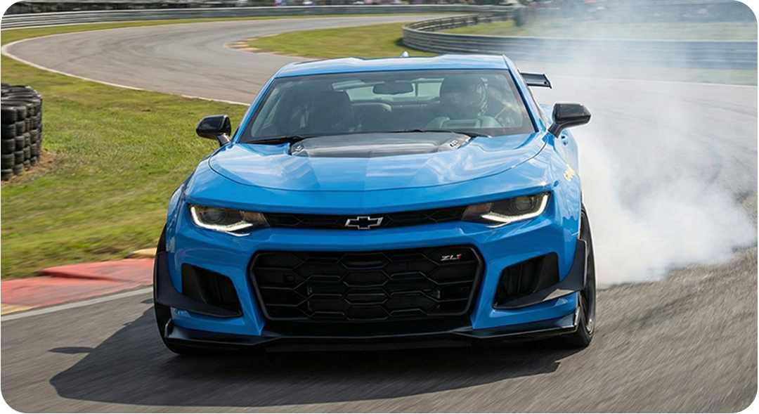 Blue Chevrolet Camaro ZL1 race car drifting on a race track, smoke coming from the tires.
