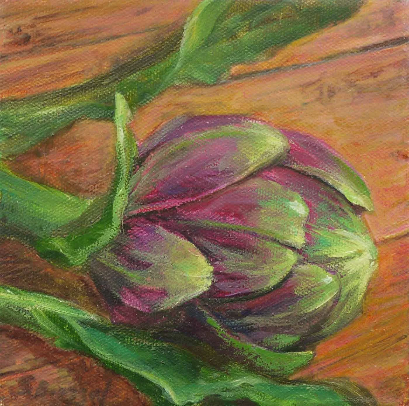 Close-up of a purple artichoke with green leaves on a wooden surface.