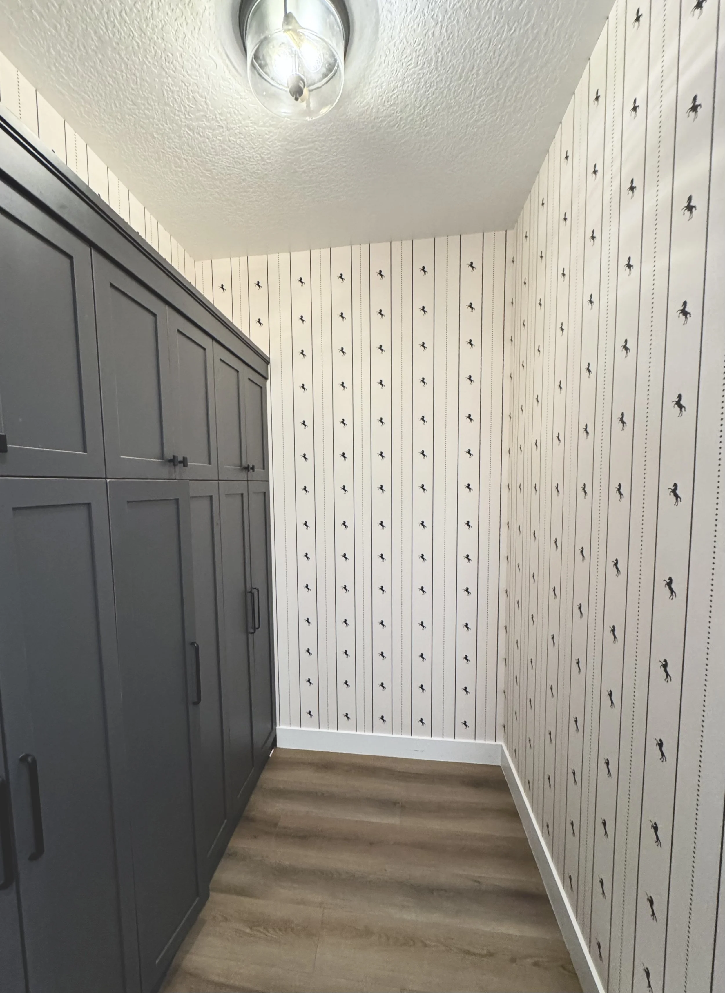 I'm Not Too Western Green Horse Wallpaper by The Torrie Jarrett Line Wall Blush wallpaper installation in a hallway and mudroom with black custom cabinets