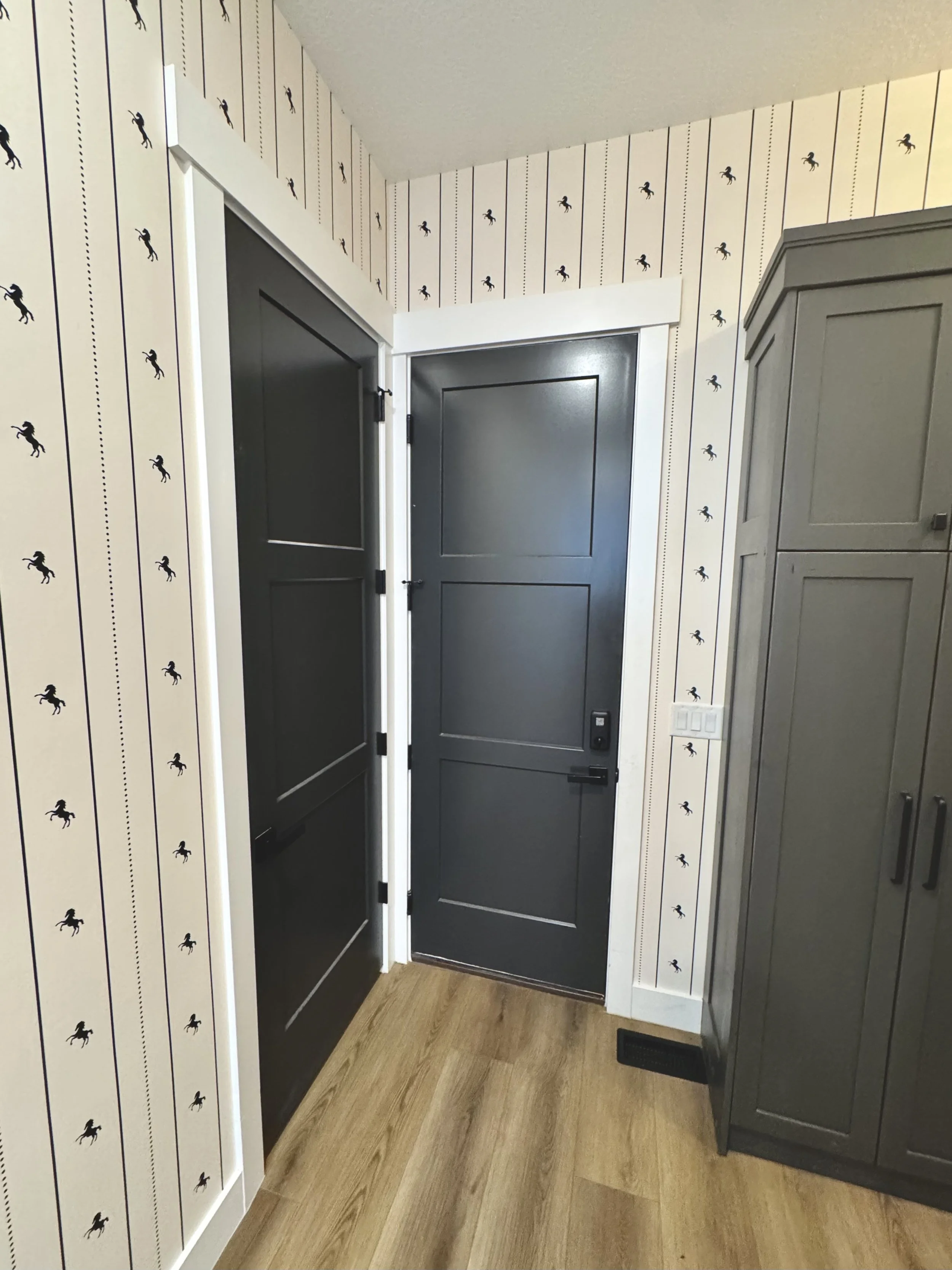 I'm Not Too Western Green Horse Wallpaper by The Torrie Jarrett Line Wall Blush wallpaper installation in a hallway with black interior doors