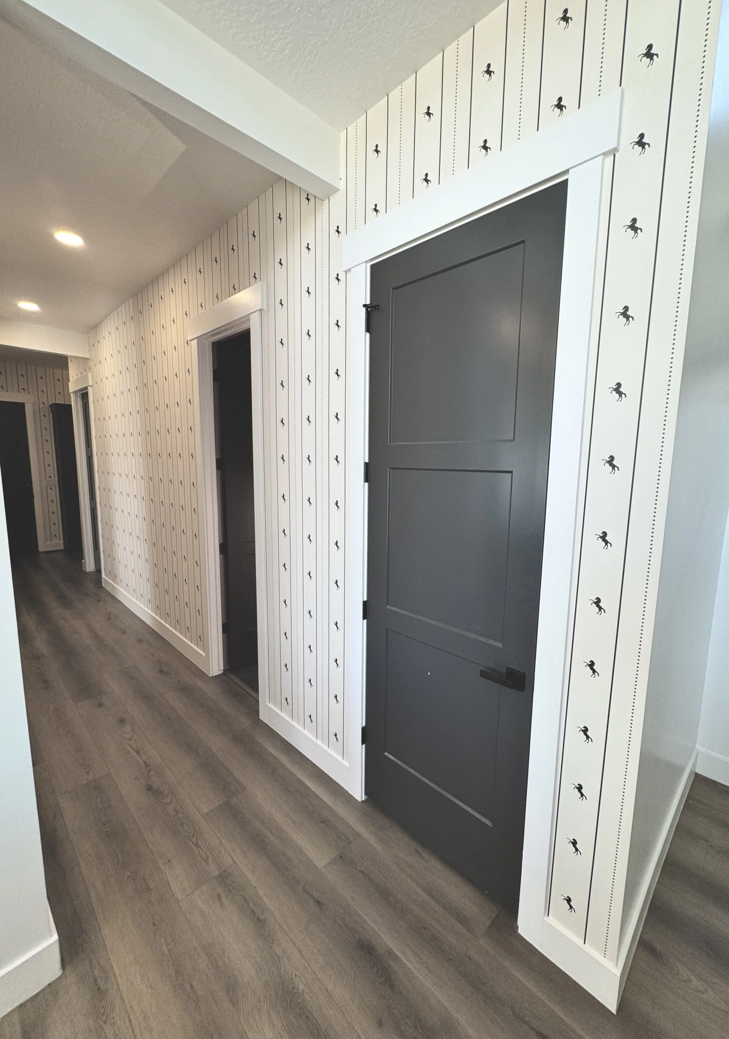 I'm Not Too Western Green Horse Wallpaper by The Torrie Jarrett Line Wall Blush wallpaper installation in a hallway with black interior doors