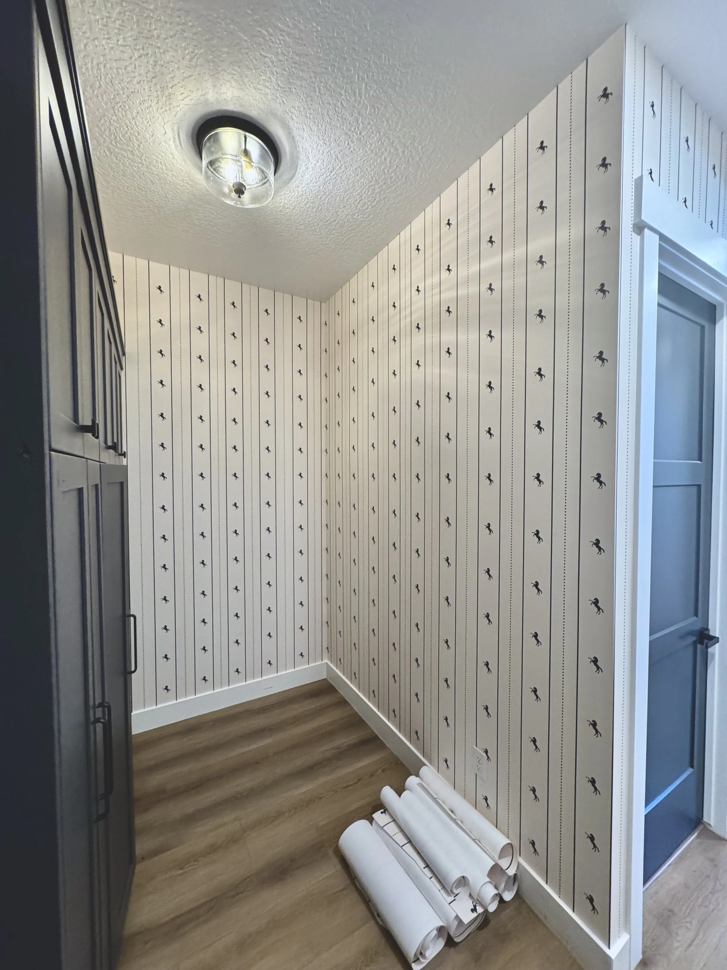 I'm Not Too Western Green Horse Wallpaper by The Torrie Jarrett Line Wall Blush wallpaper installation in a hallway with black custom. cabinets