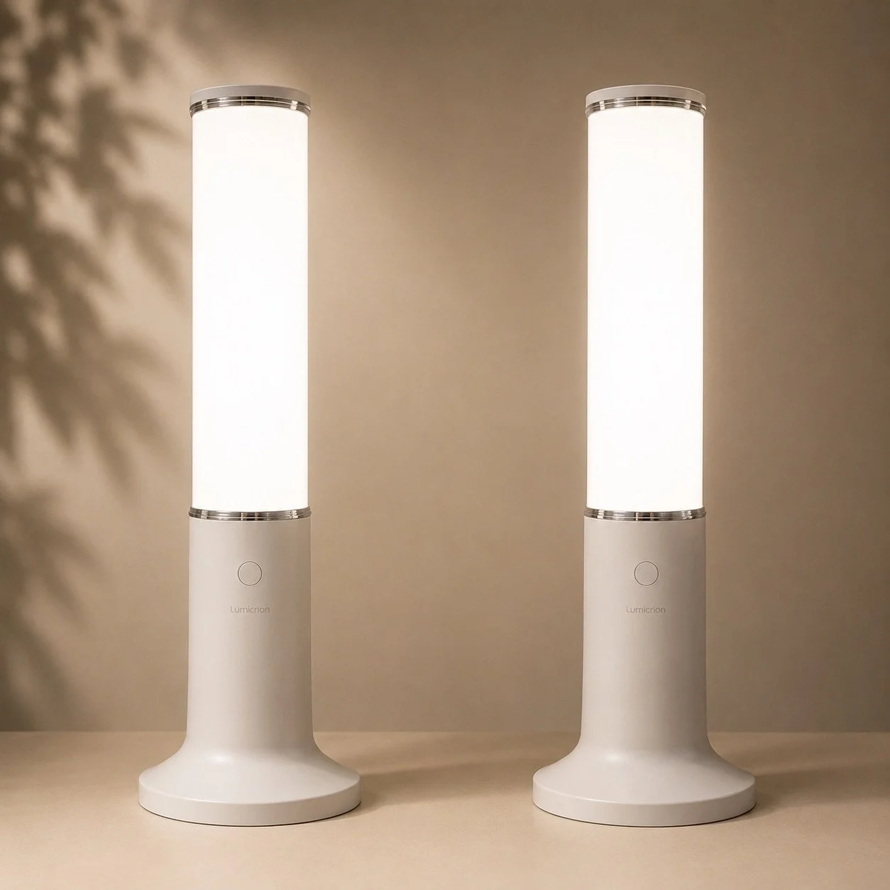Two white modern lamps with cylindrical shades and round bases on a beige surface, casting shadows on a beige wall.
