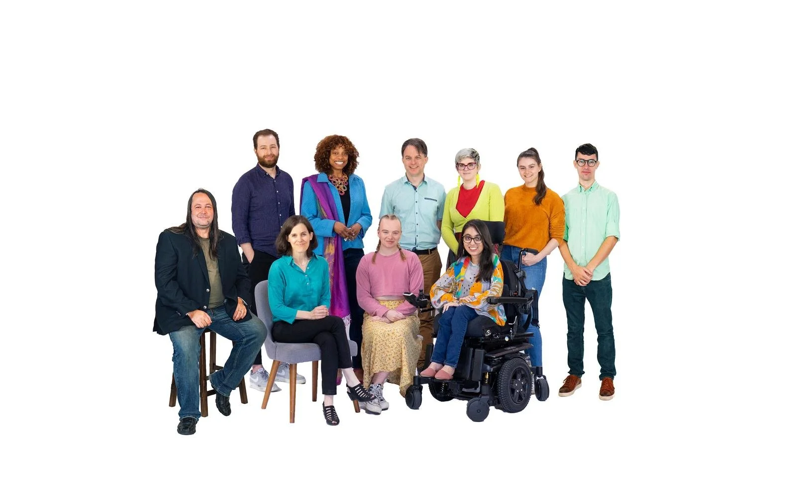 A group shot of several people, some standing and some sitting or using mobility aids, smiling to camera. They're against a white background.