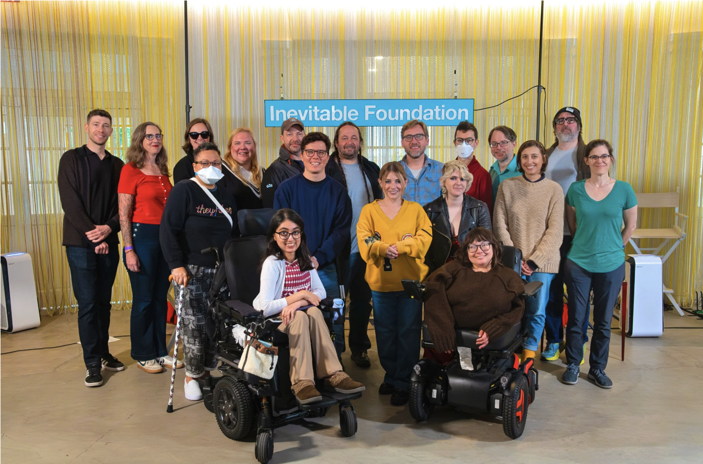 An image of a group of fellows, some with mobility aids and some wearing masks, smiling at the camera.