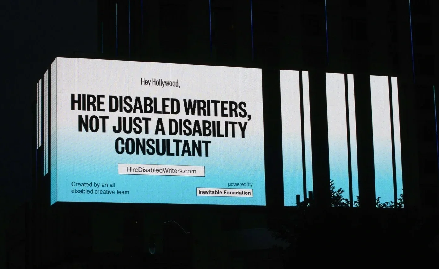 A blue and white billboard that says, "Hire disabled writers, not just a disability consultant."
