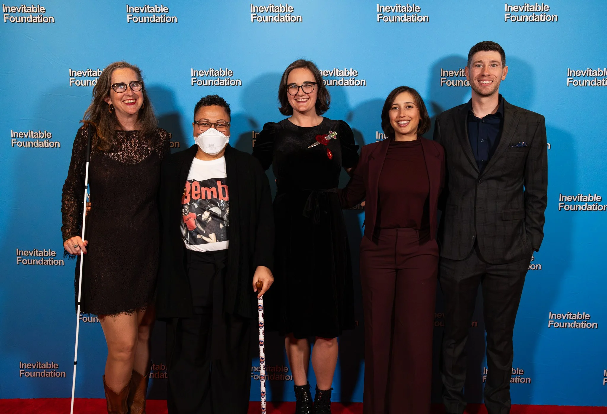 A group of Visionary Fellowship alumni, smiling on a red carpet with a blue background