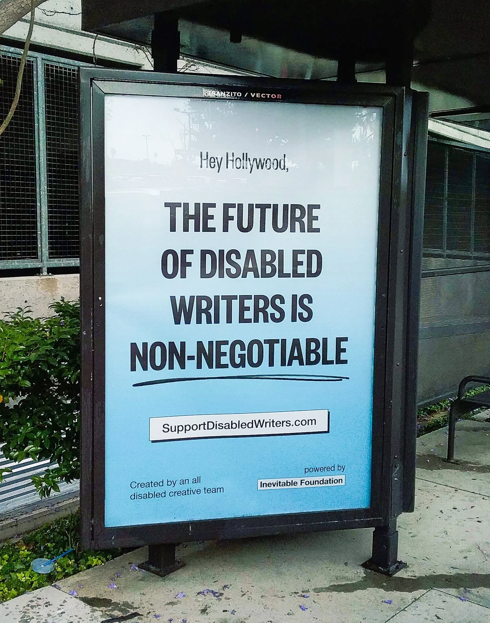 A large sign on a street that says, "The future of disabled writers is non-negotiable." The sign is blue and white.
