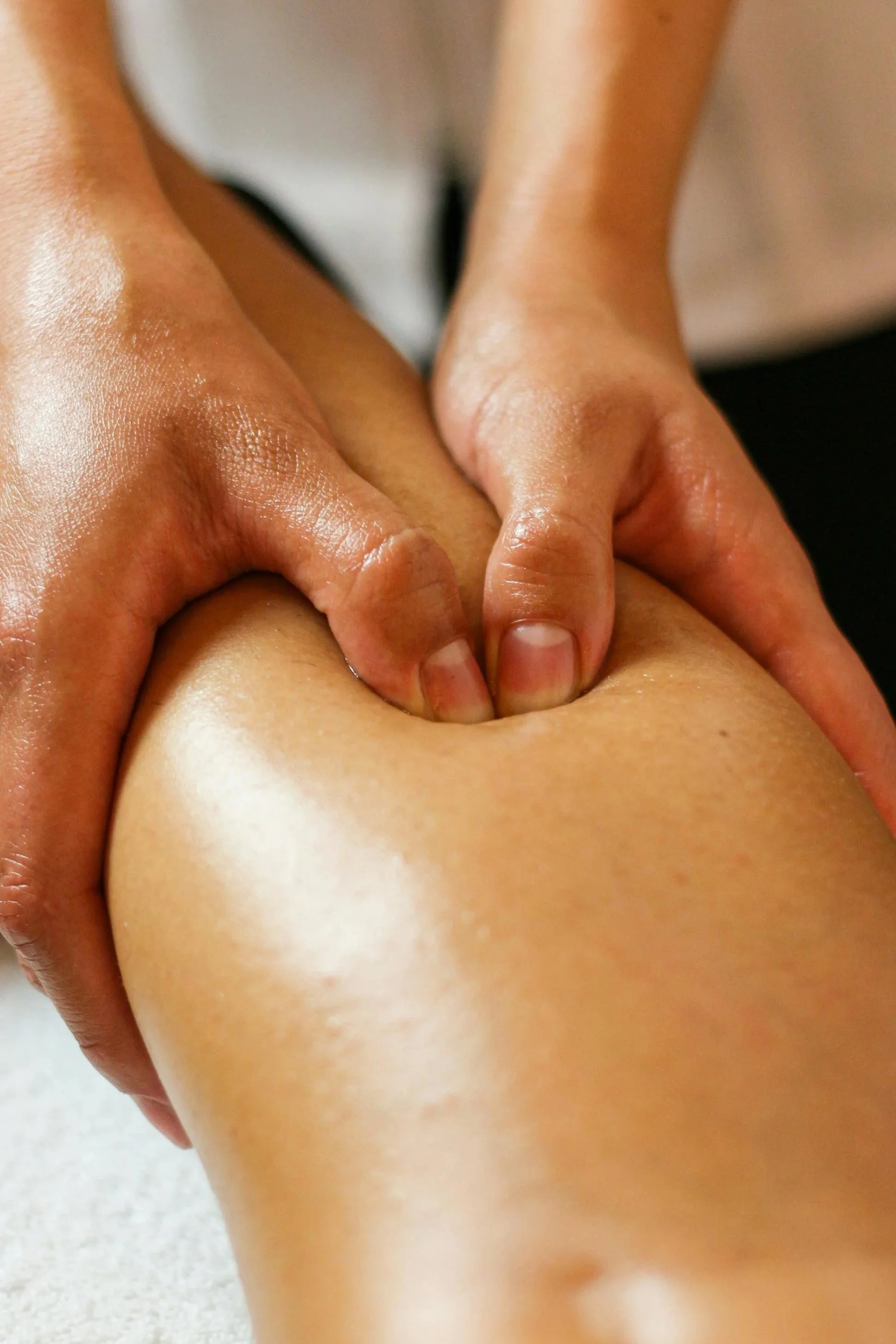 Close-up of a person receiving a massage on their thigh, focusing on the hands applying pressure.
