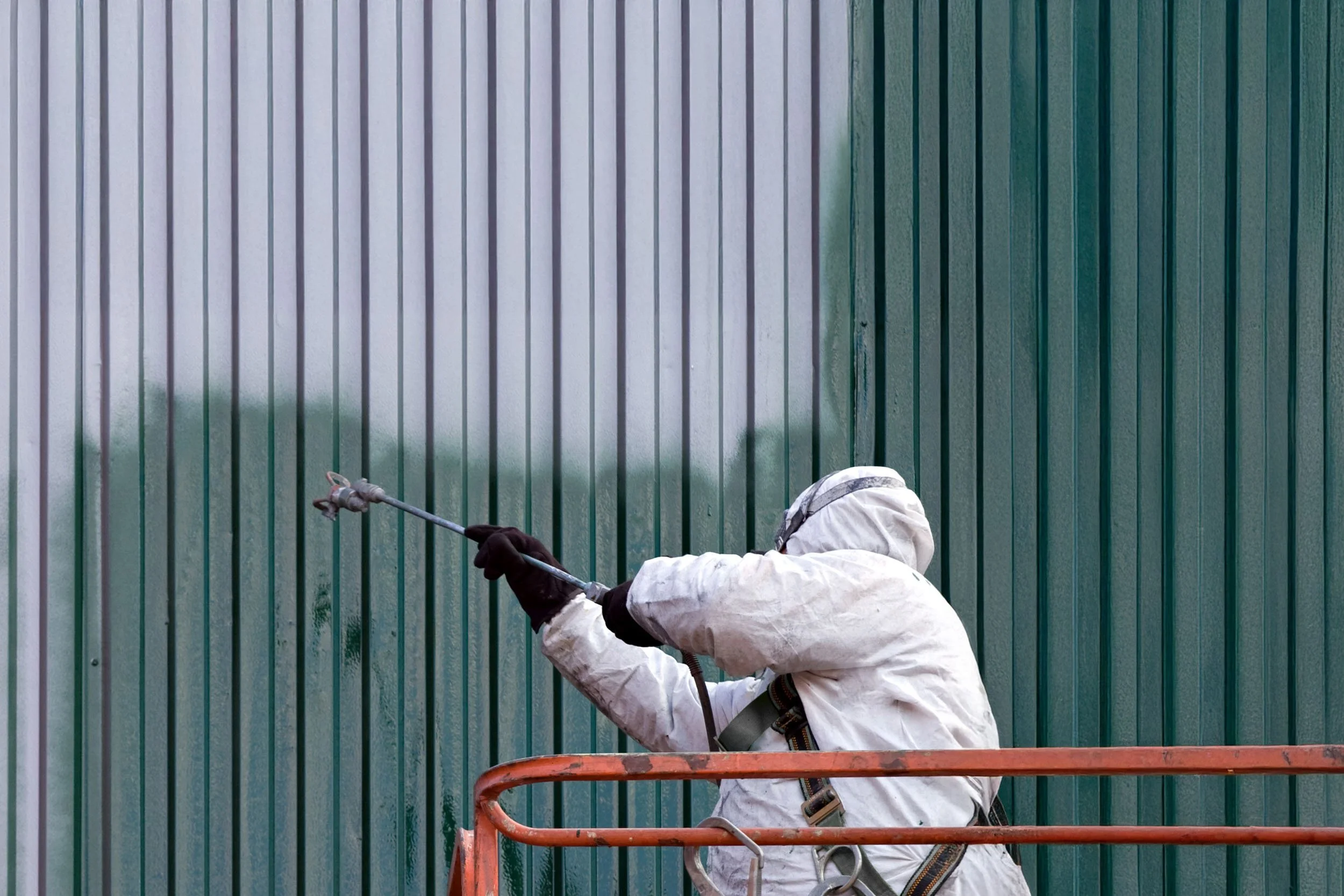 Commercial exterior painting on metal wall using spray equipment in Charlotte NC