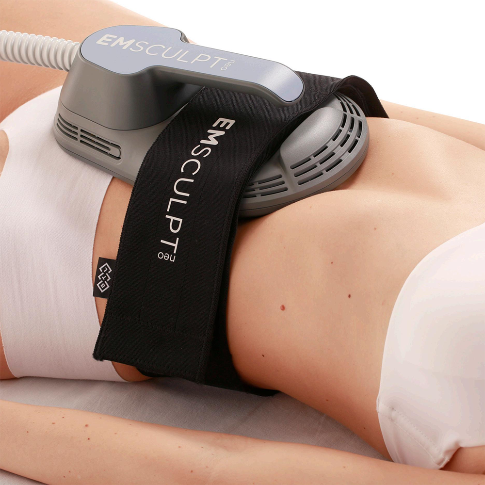 Close-up of a person receiving an EMSculpt Neo treatment on their abdomen, with a medical device labeled EMSculpt Neo placed on their stomach and secured with a strap.