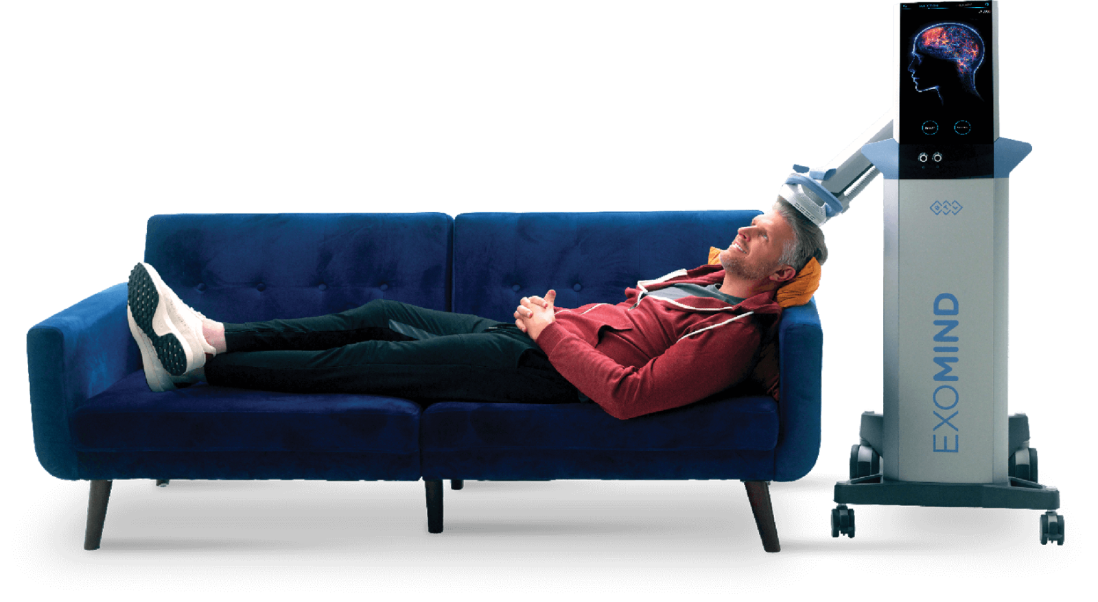 A man lying on a blue couch with an ExoMind brain stimulation device attached to his head, smiling with eyes closed.