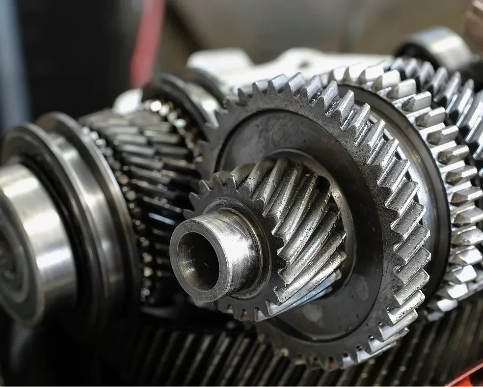 Close-up of metallic gears and gear shafts, likely part of a mechanical transmission system.