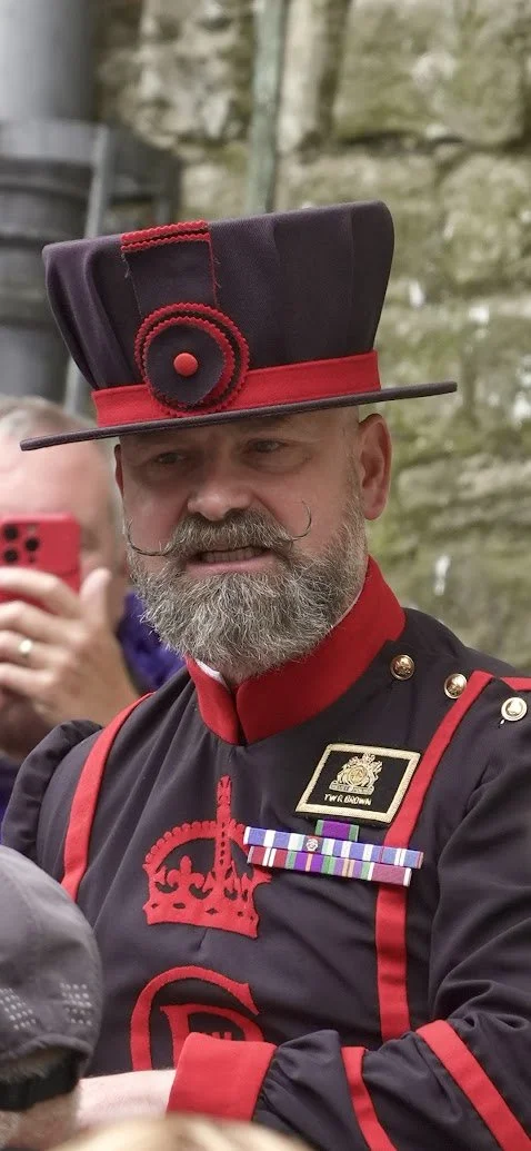 Man dressed in a historic military uniform with a distinctive tall hat, gray beard, and medals.