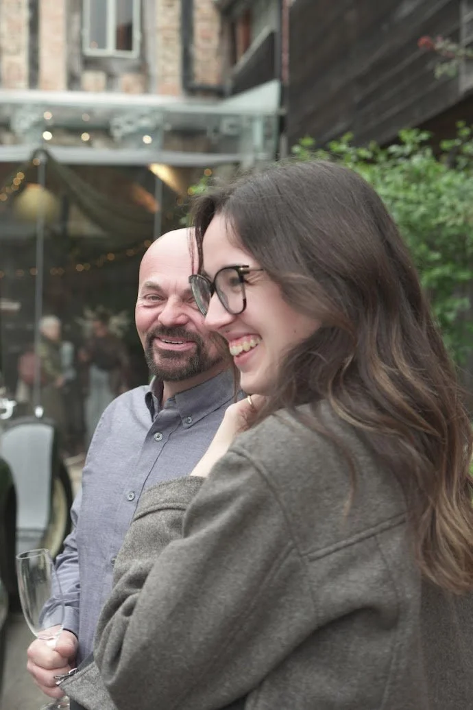 A man and woman smiling and enjoying each other's company outdoors at a gathering or party.