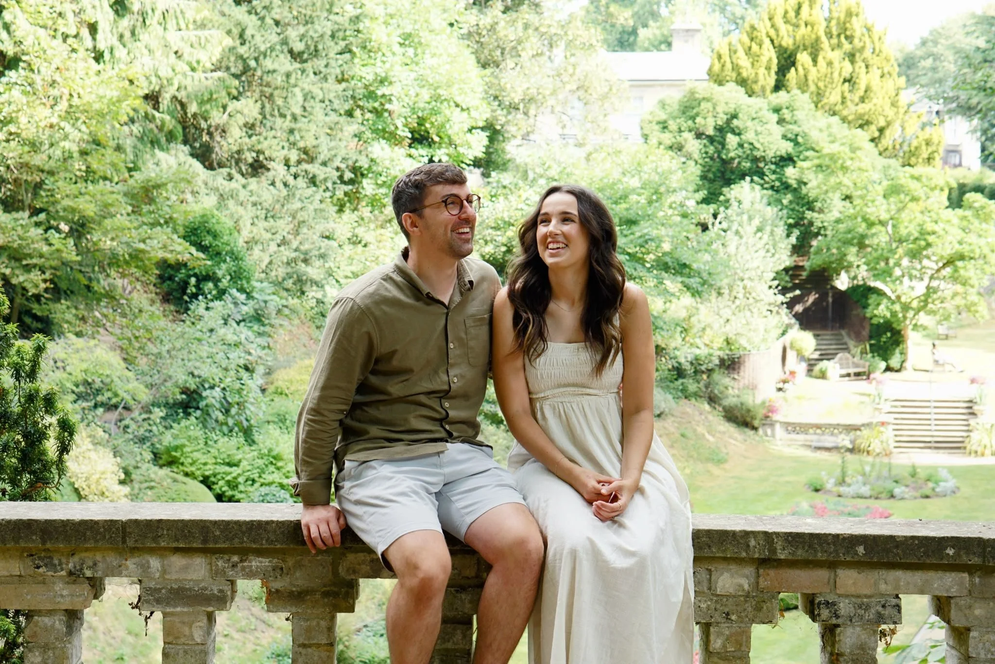 An engaged couple laughing together during a relaxed pre-wedding photo shoot in a Norfolk garden.