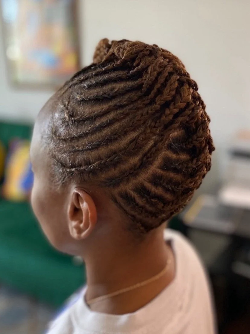 A woman with styled brown dreadlocks tied into an updo, viewed from the side.