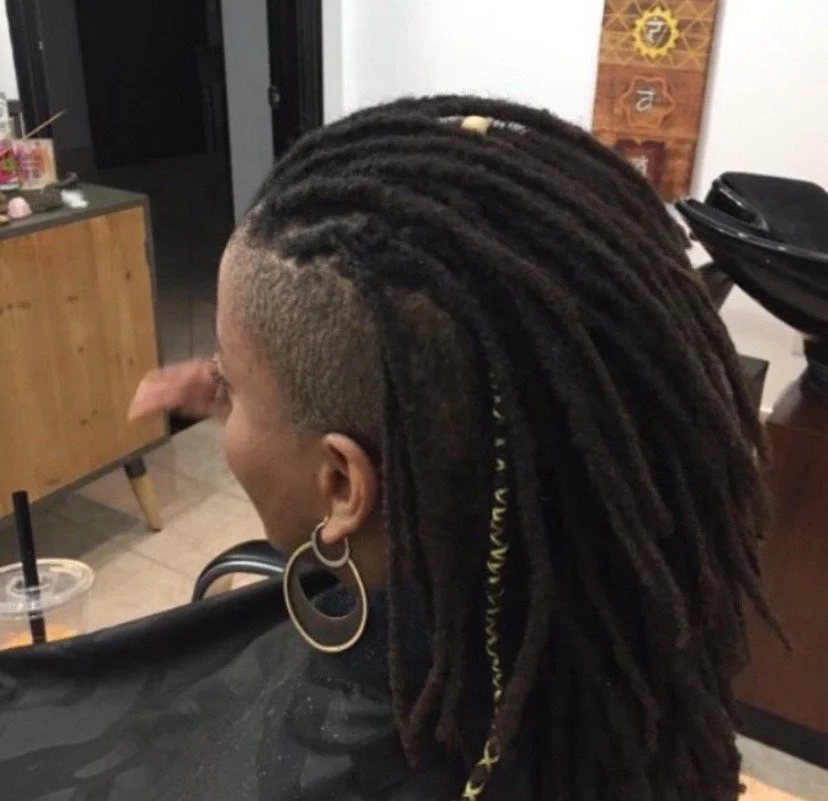 A person with a mohawk and dreadlocks sitting in a hair salon.