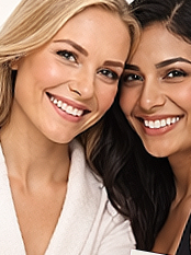 Close-up of two women smiling, one with blonde hair and one with dark hair.