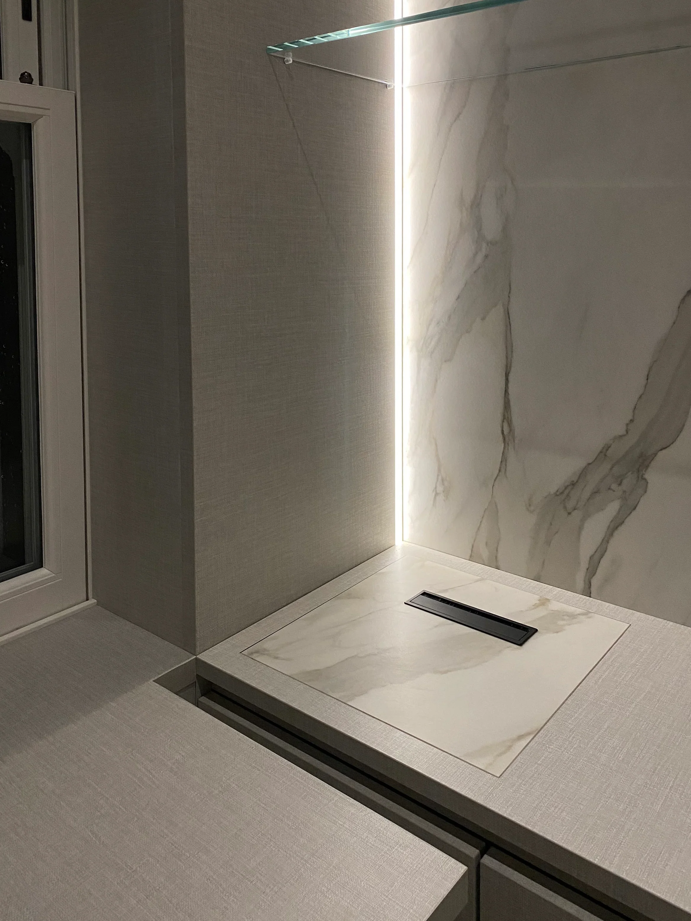 A luxury study room desk featuring a textured fabric-effect porcelain worktop with a seamlessly integrated pop-up charging port and connectivity hub by PietraCasa.