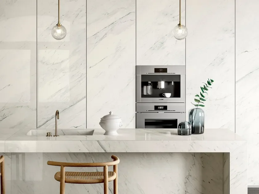 High-end kitchen featuring SapienStone Premium White porcelain stoneware on the worktop and continuous wall cladding for a seamless, monolithic look, supplied by PietraCasa.