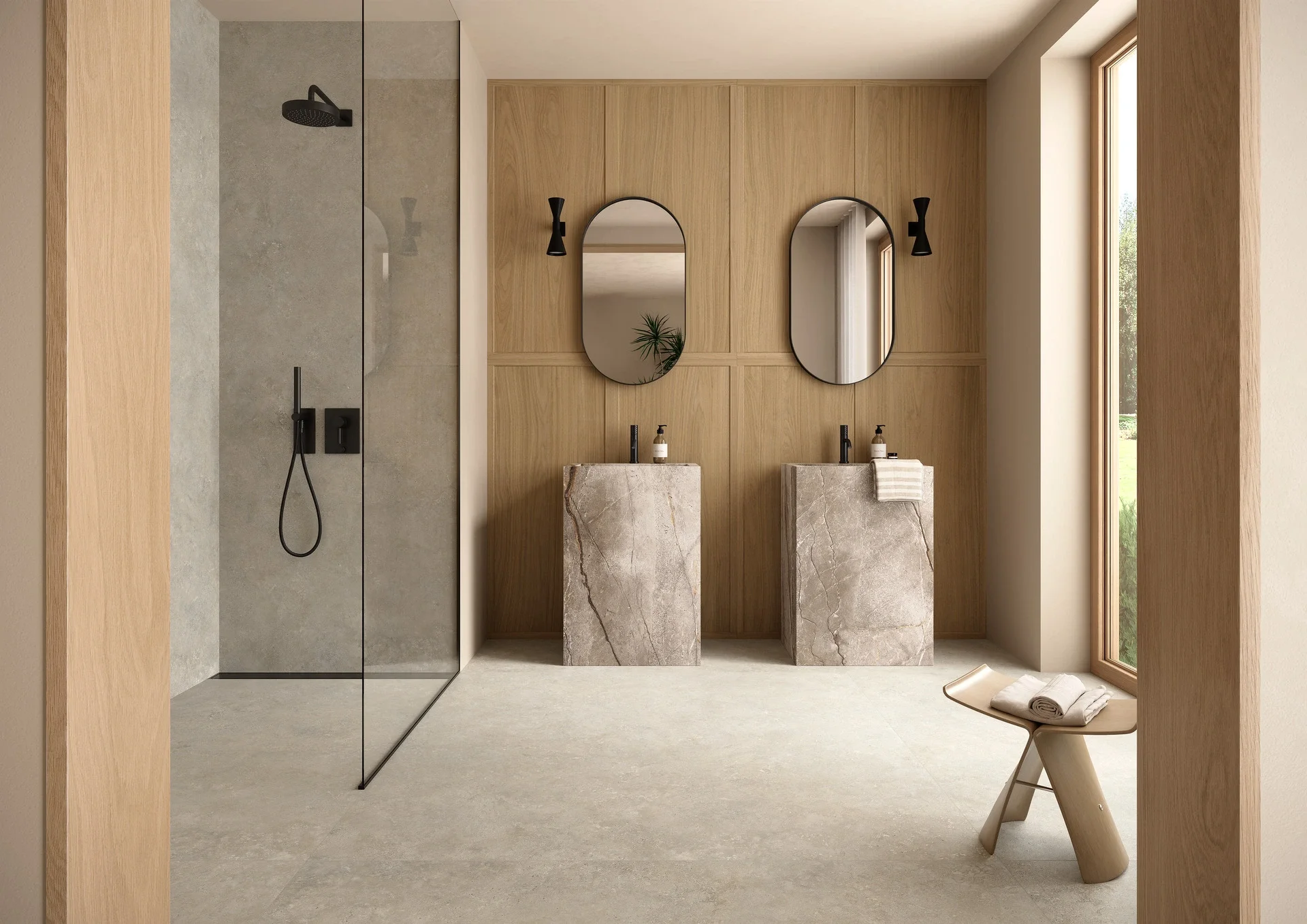 Minimalist bathroom featuring Marazzi Mystone Tivoli tiles on the floor and walls, paired with a warm timber panel feature wall, dual stone-clad pedestal sinks, and sleek black fixtures, available through PietraCasa.