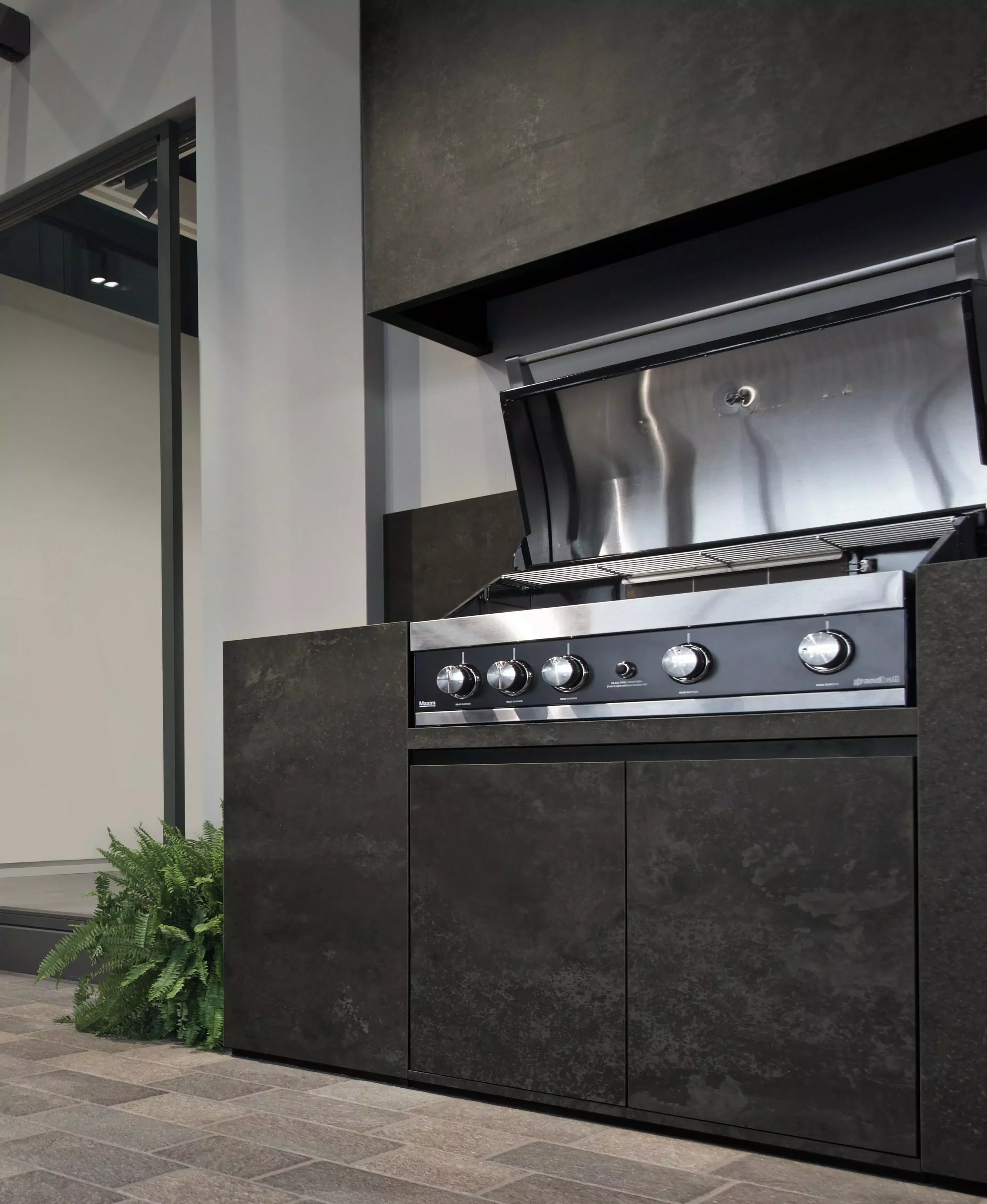 Modern outdoor kitchen island clad in durable FLORIM stone porcelain slabs, featuring a sleek, integrated built-in gas barbecue grill, expertly supplied and installed by PietraCasa.