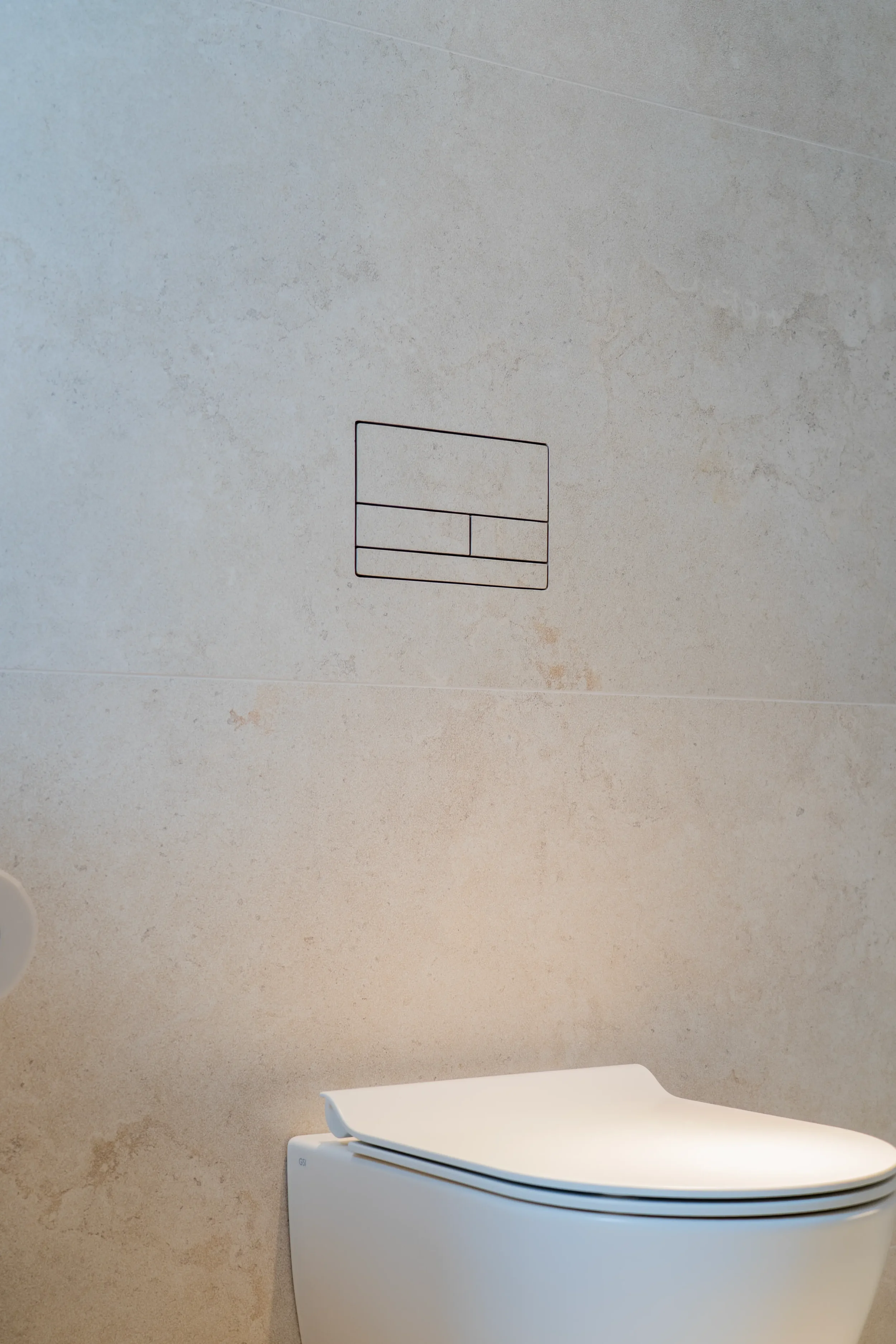 Close-up detail of a minimalist Clanea flush plate seamlessly integrated into high-end stone-look porcelain wall tiles, supplied and installed by PietraCasa.