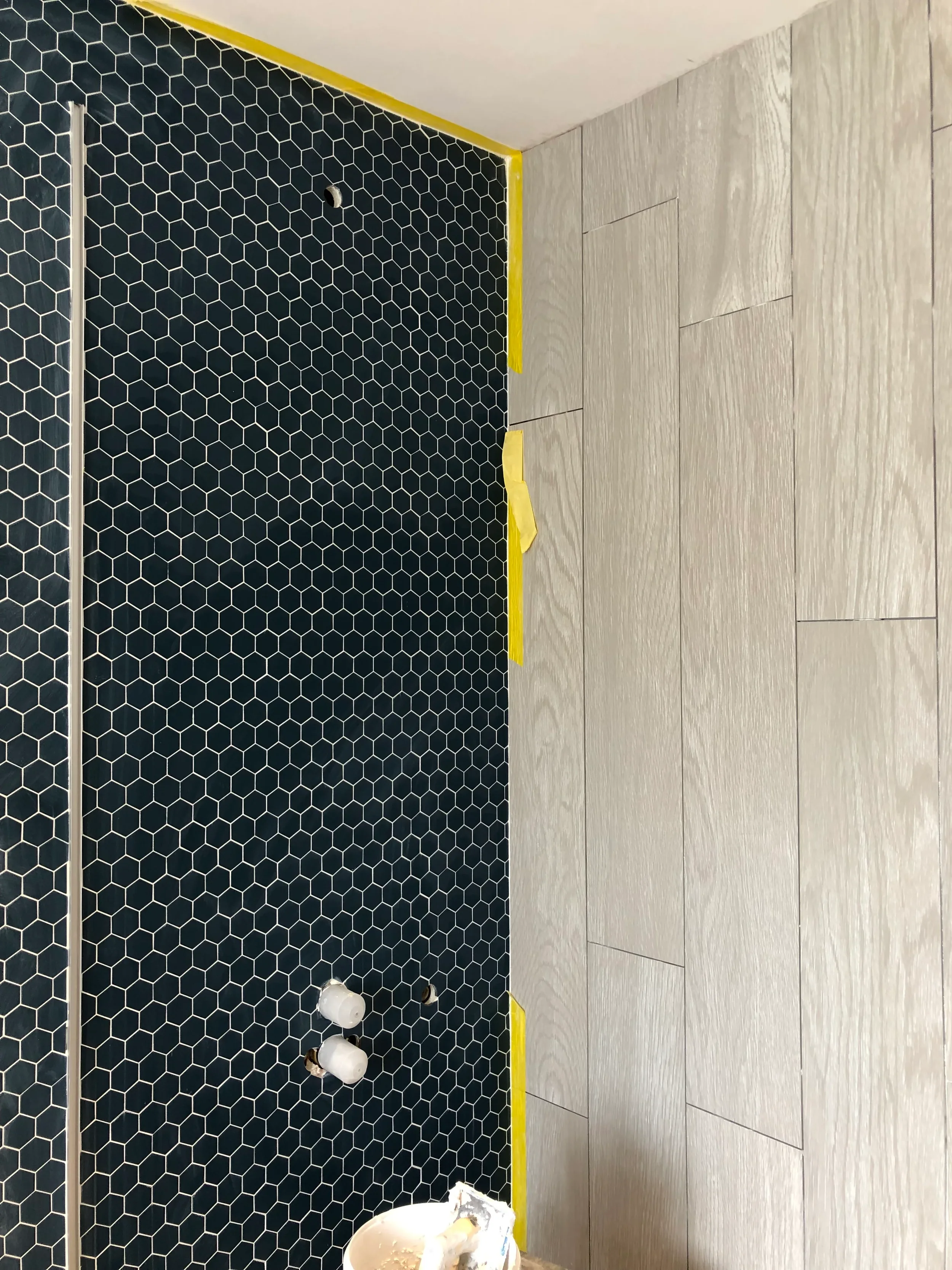 Blue hexagon mosaic tiles next to wood-effect porcelain tiling during installation, designed by Pietracasa and Abitalia.