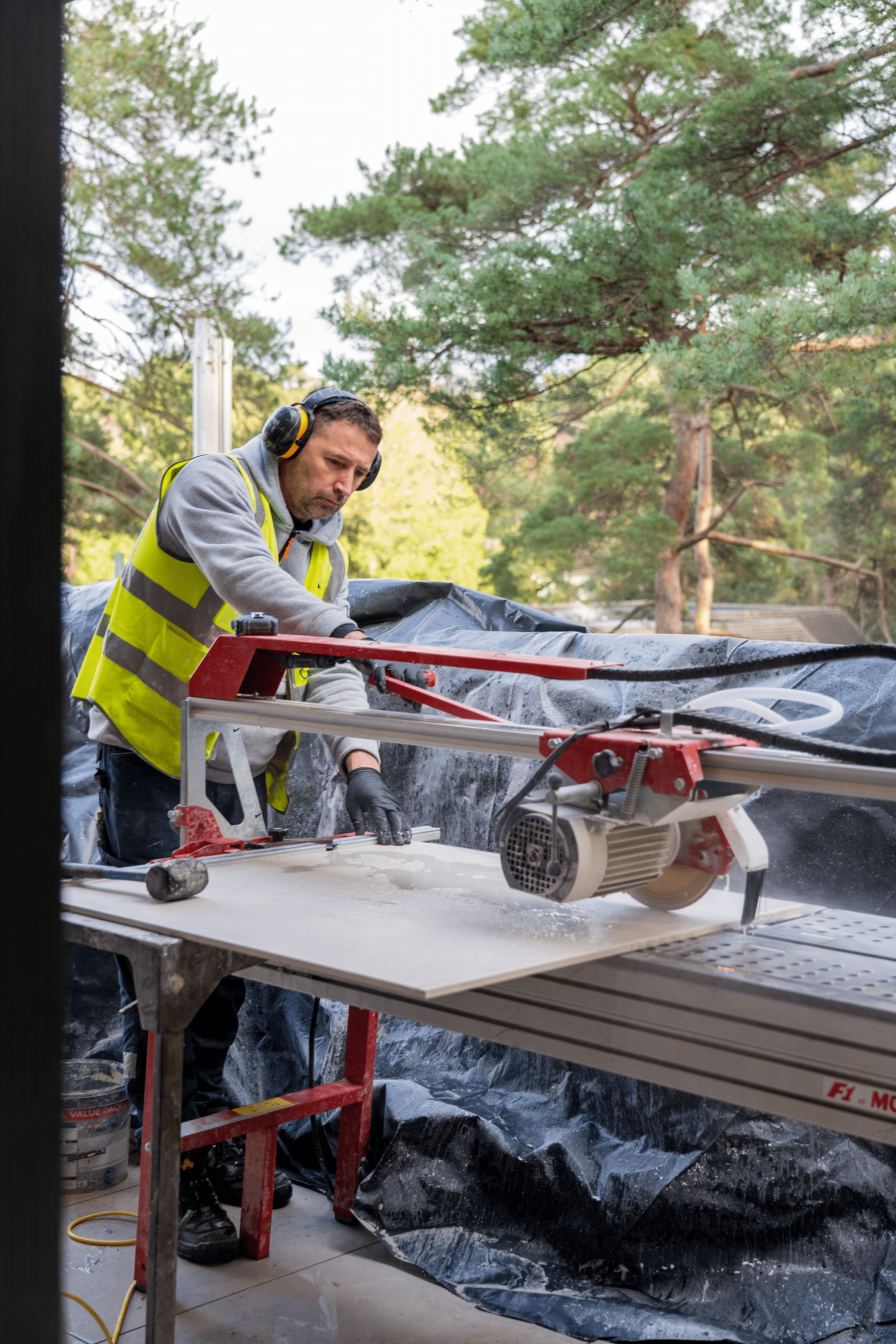 Professional tile installer using a Montolit wet saw to precision-cut a large-format porcelain tile for a custom PietraCasa fabrication project.