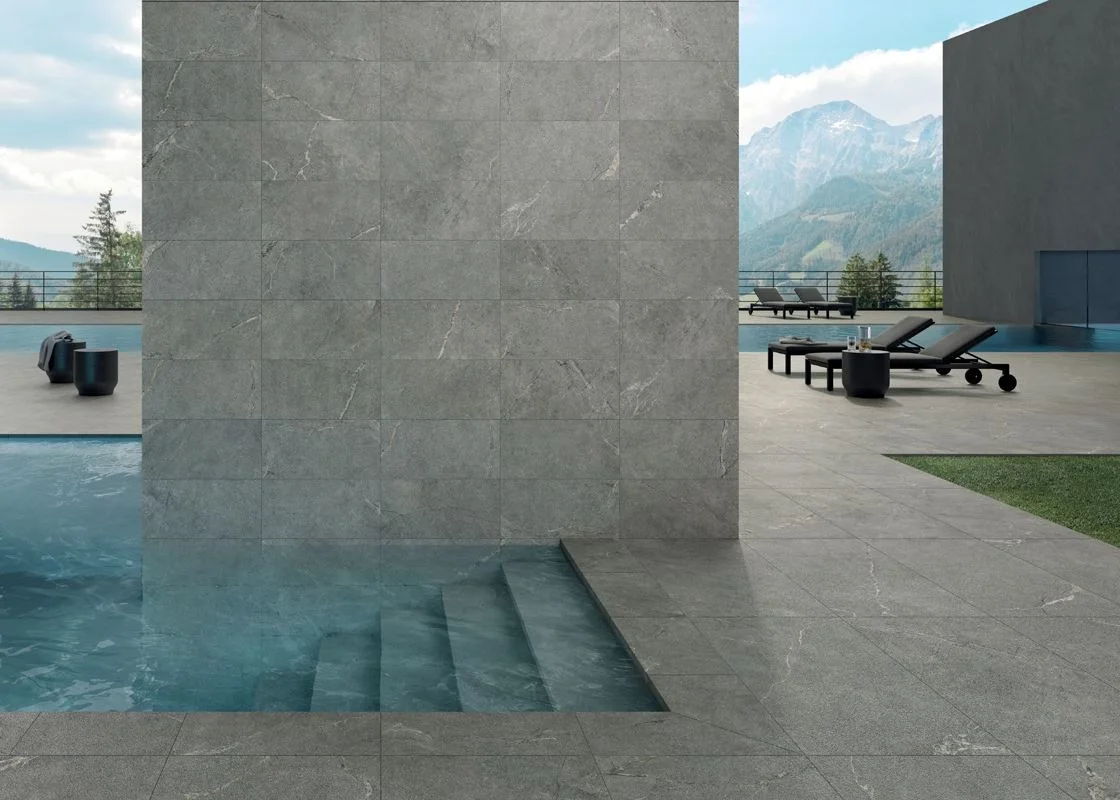 A serene pool setting featuring Lea Ceramiche's Anthology porcelain stoneware in the 04 Gray Rough finish, celebrated for its natural stone aesthetic and durability, available through PietraCasa.