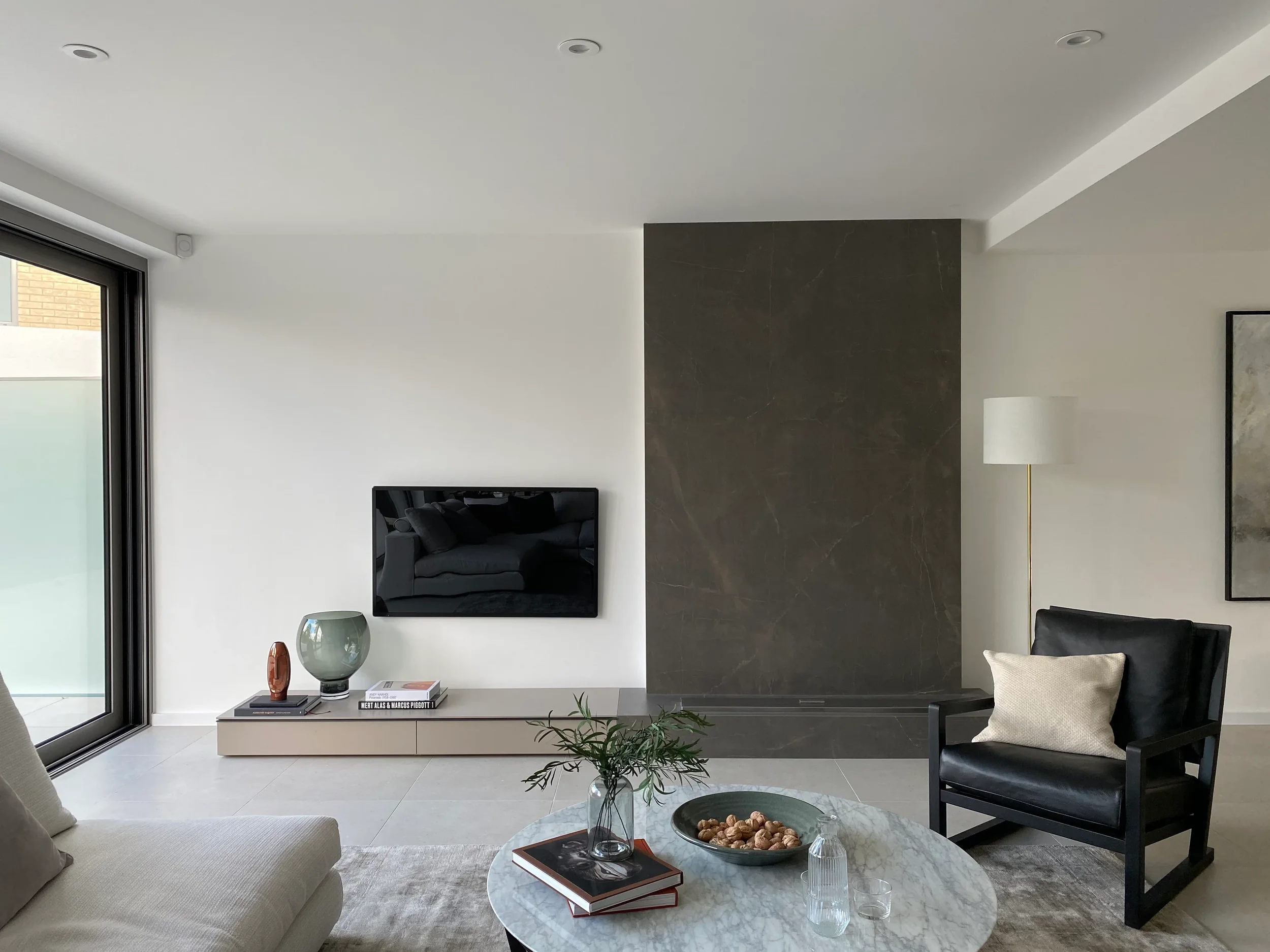 A sophisticated, minimalist living space featuring a dramatic, dark porcelain feature wall and a sleek, low-profile media unit, creating a refined and high-end aesthetic.
