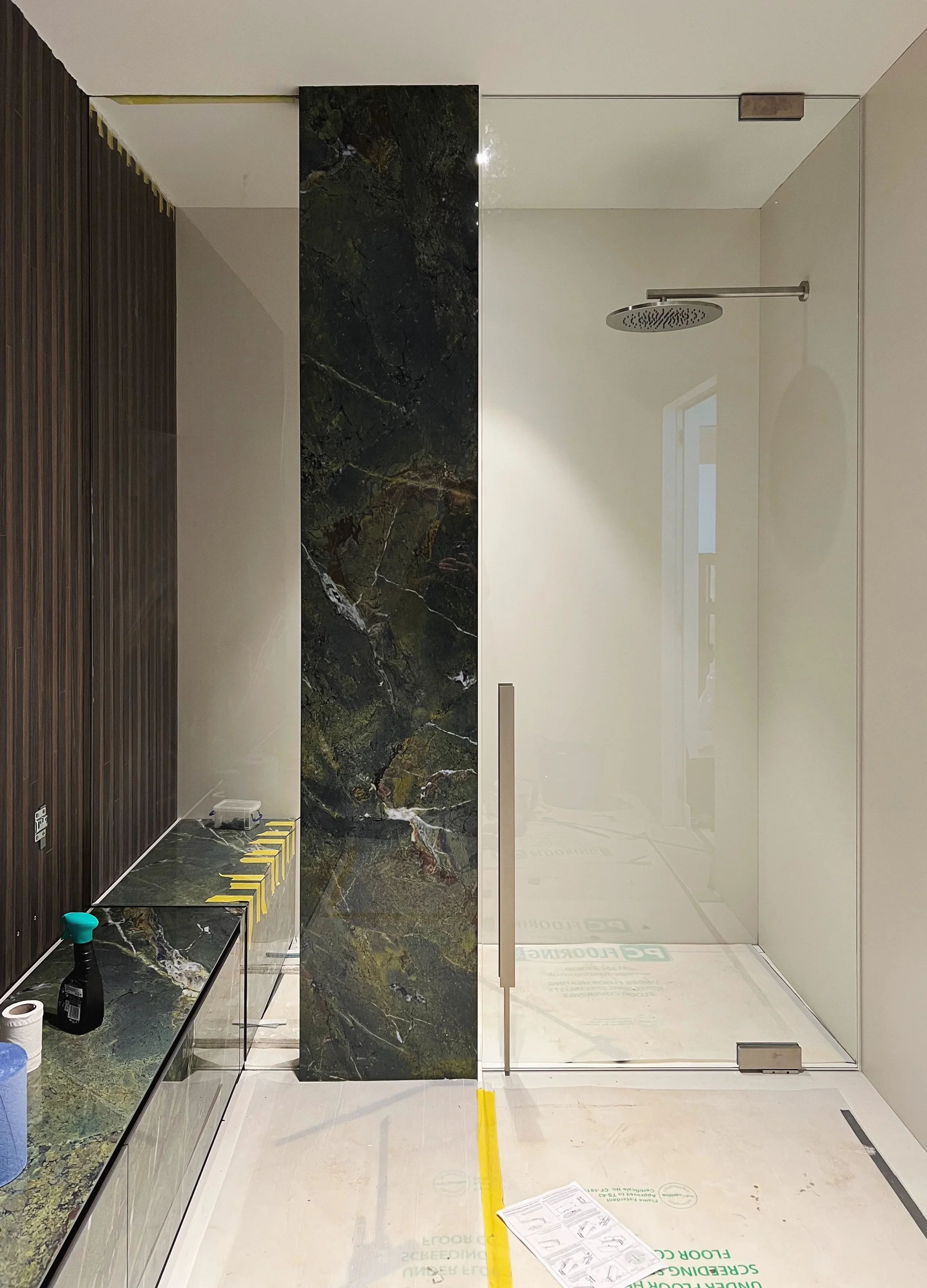A high-end bathroom interior featuring a striking, large-format florim heritage emerald porcelain vertical feature, creating a bold and luxurious design statement.