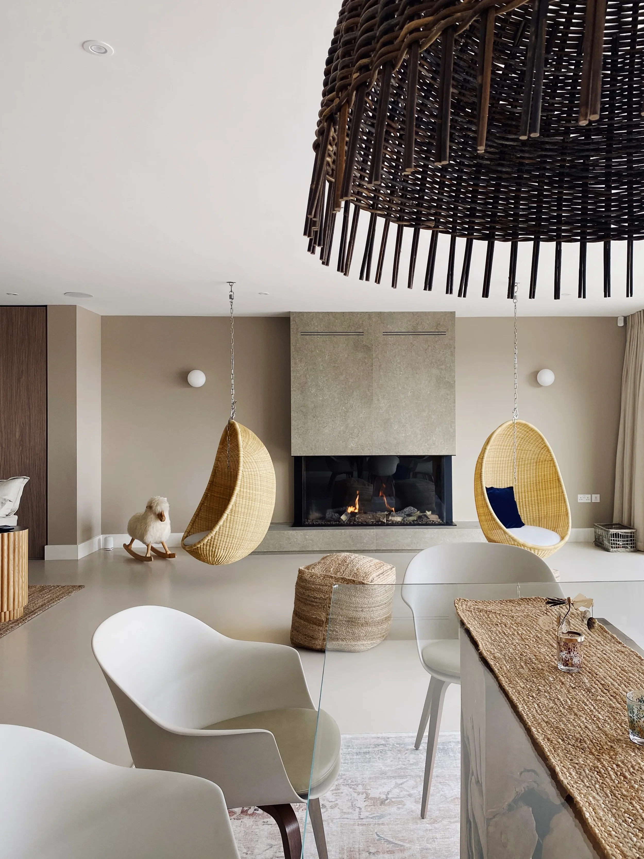 A luxury contemporary open-plan living room featuring a tall structural chimney breast custom-fabricated from stone-effect large-format porcelain panels, integrated seamlessly with a modern linear glass fireplace.